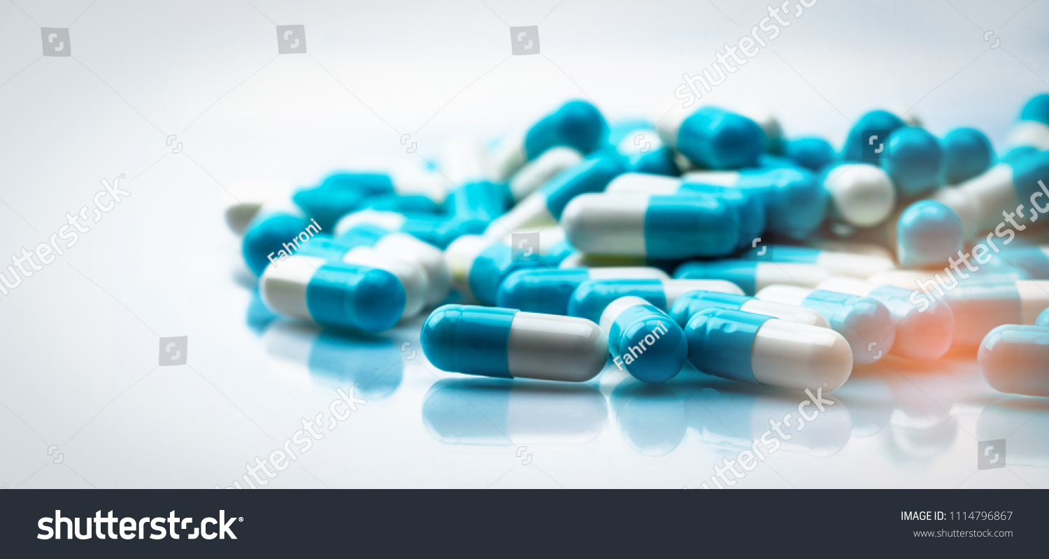Selective focus on blue and white capsules pill on white background. Antibiotics drug resistance. Antimicrobial capsule pills. Pharmaceutical industry. Pharmacy drugstore products. Pharmaceutics. #1114796867