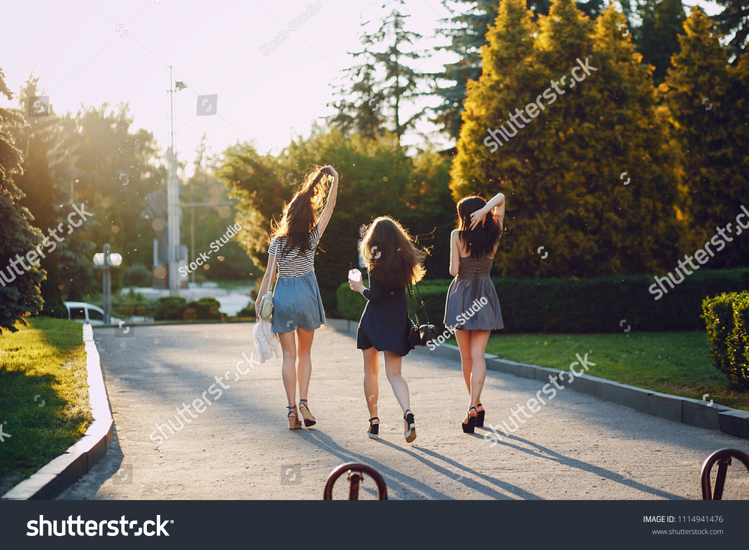 Three beautiful girls walking in the summer sunny city with coffee #1114941476