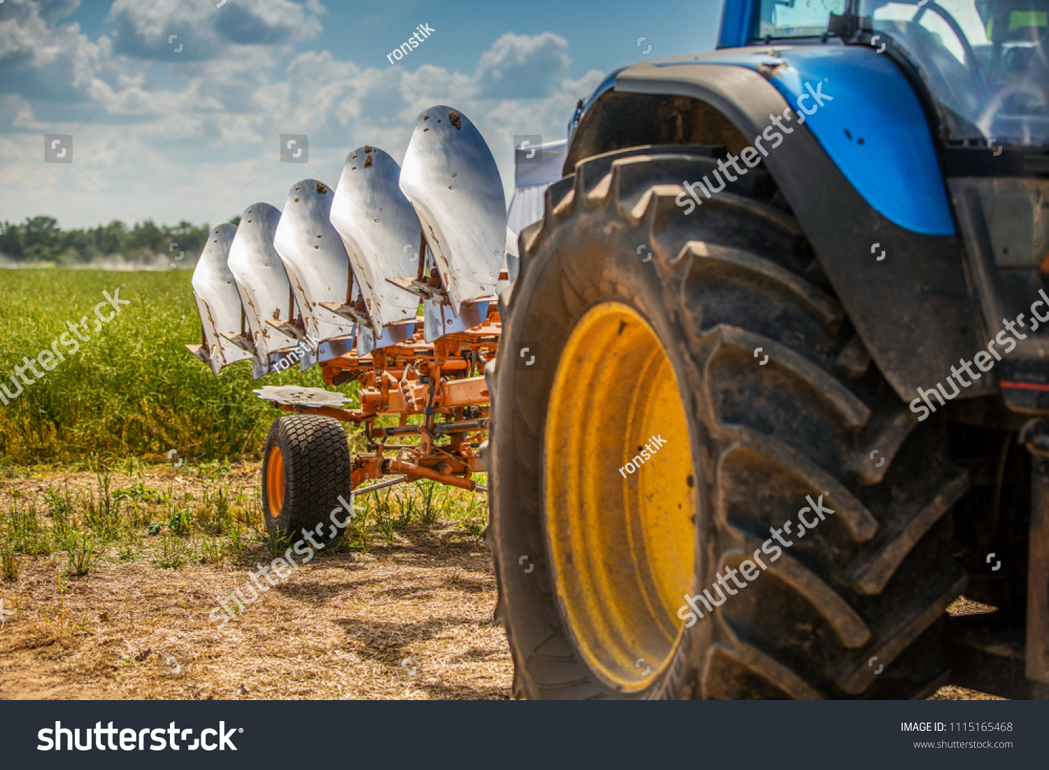 tractor with plough beside the field #1115165468