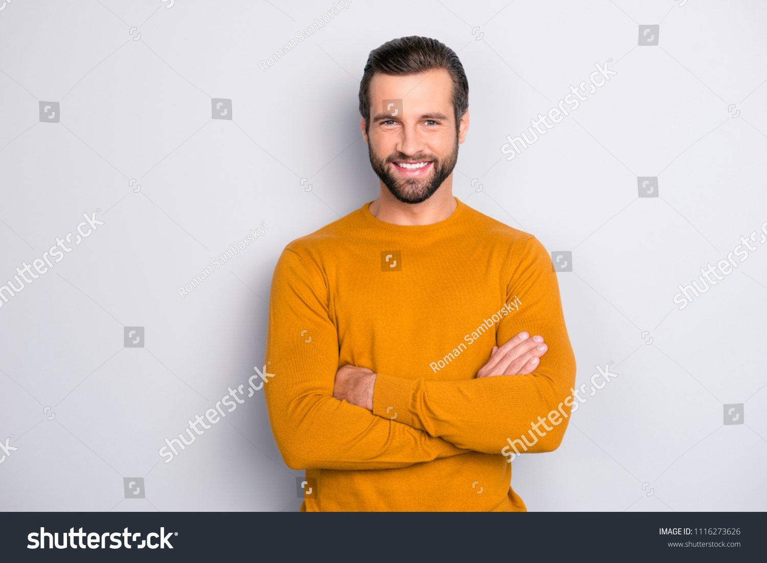 Portrait of attractive self-assured with beaming shiny smile haircut with long furfur wearing casual classic color of mustard sweater macho man standing with folded arms isolated on gray background #1116273626
