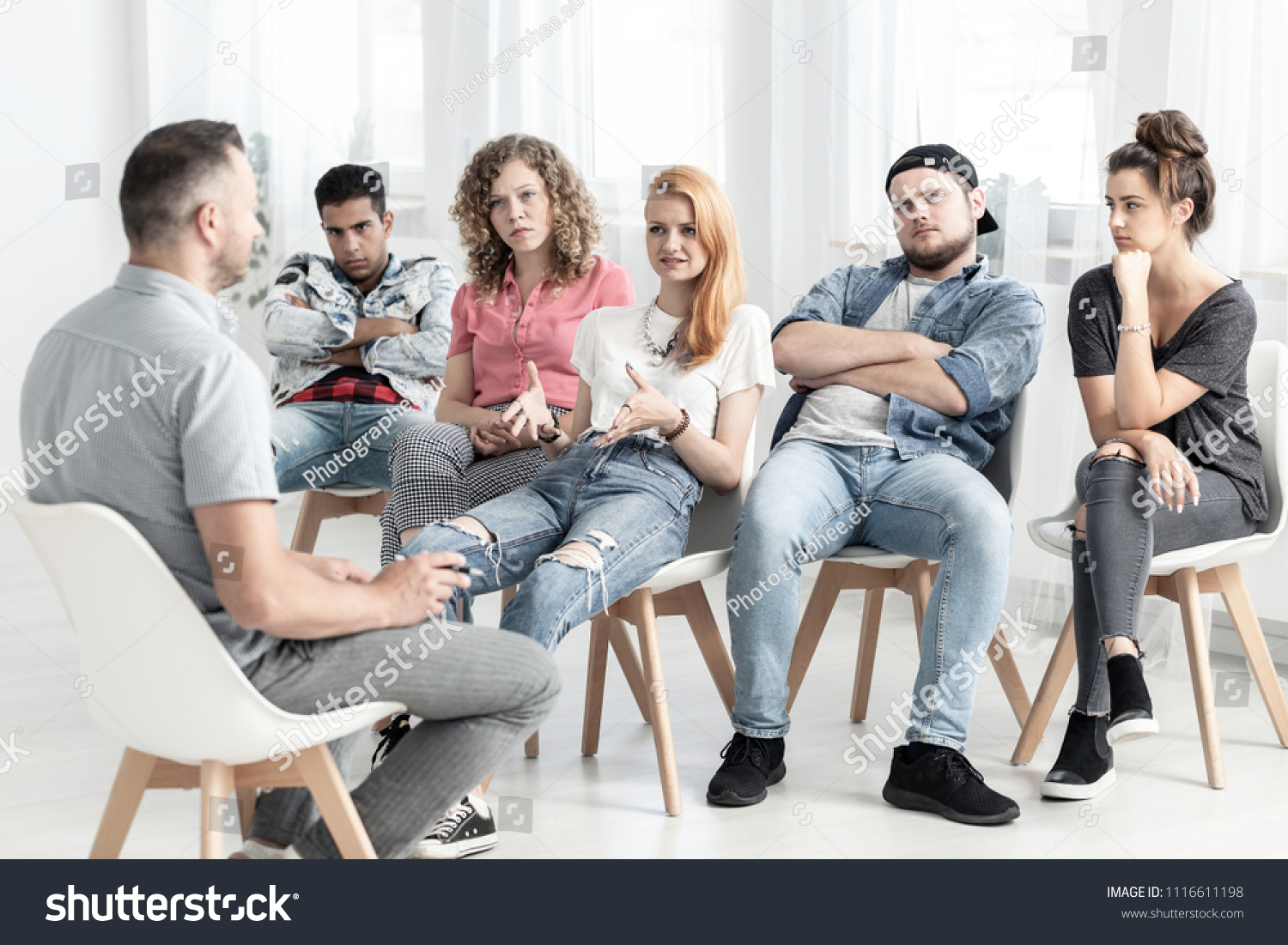 Group of rebellious teenagers talking to a psychotherapist about bullying in their school #1116611198