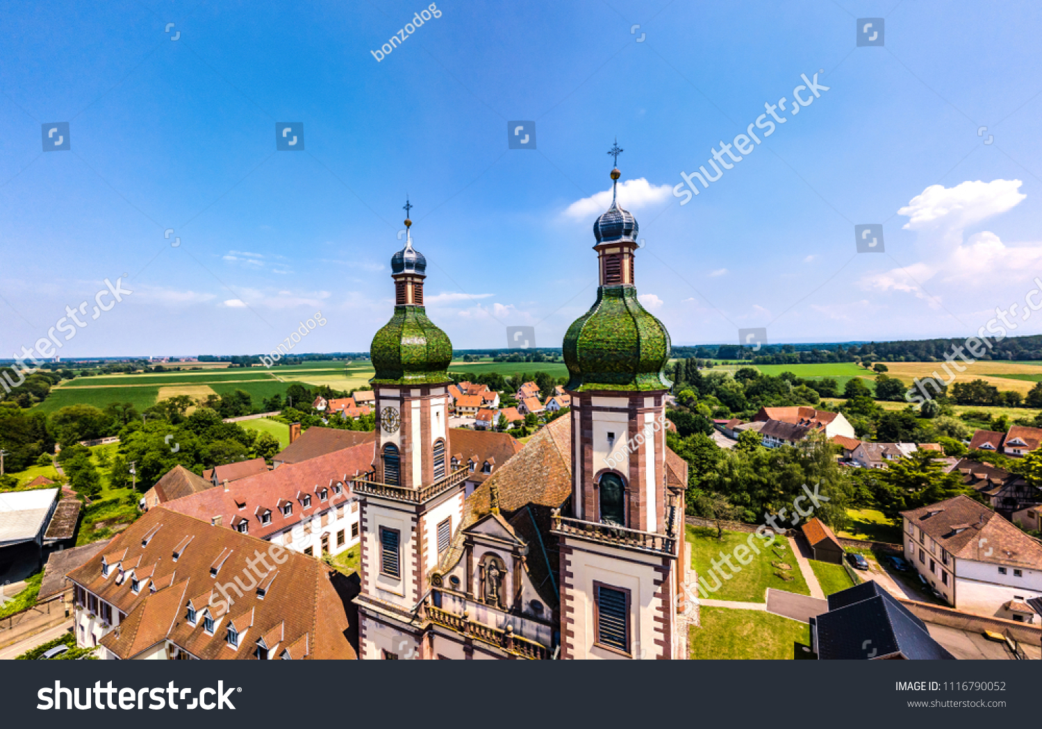 Soaring majestic church Saint Maurice in little french village Ebersmunster. Aerial drone view. Alsace. France. #1116790052