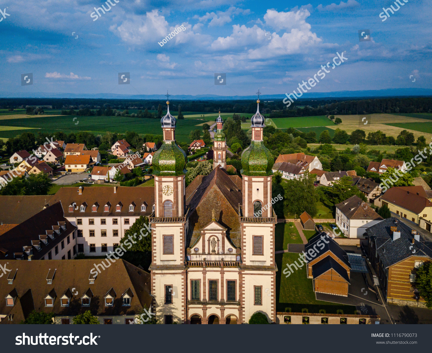Soaring majestic church Saint Maurice in little french village Ebersmunster. Aerial drone view. Alsace. France. #1116790073