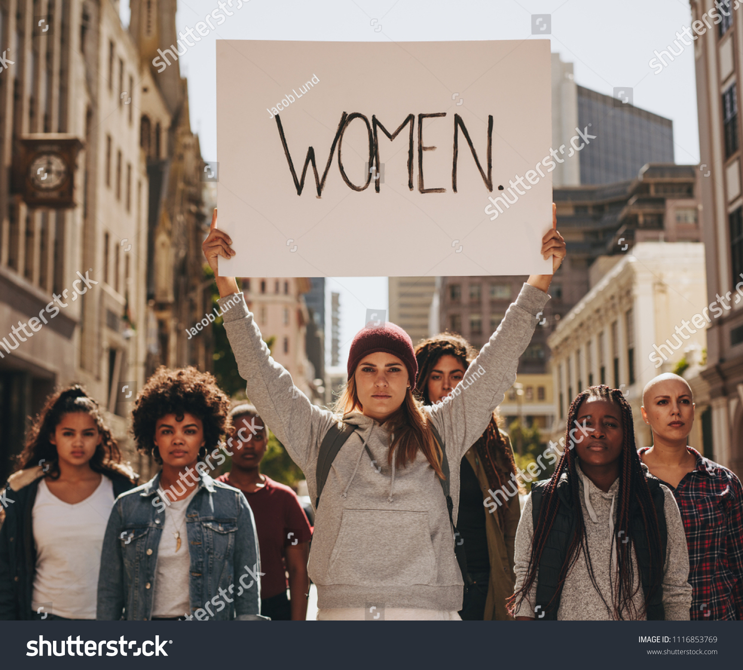 Group of females protesters marching on the road with signboard of women. Woman holding a protest sign about women empowerment with group of females around. #1116853769