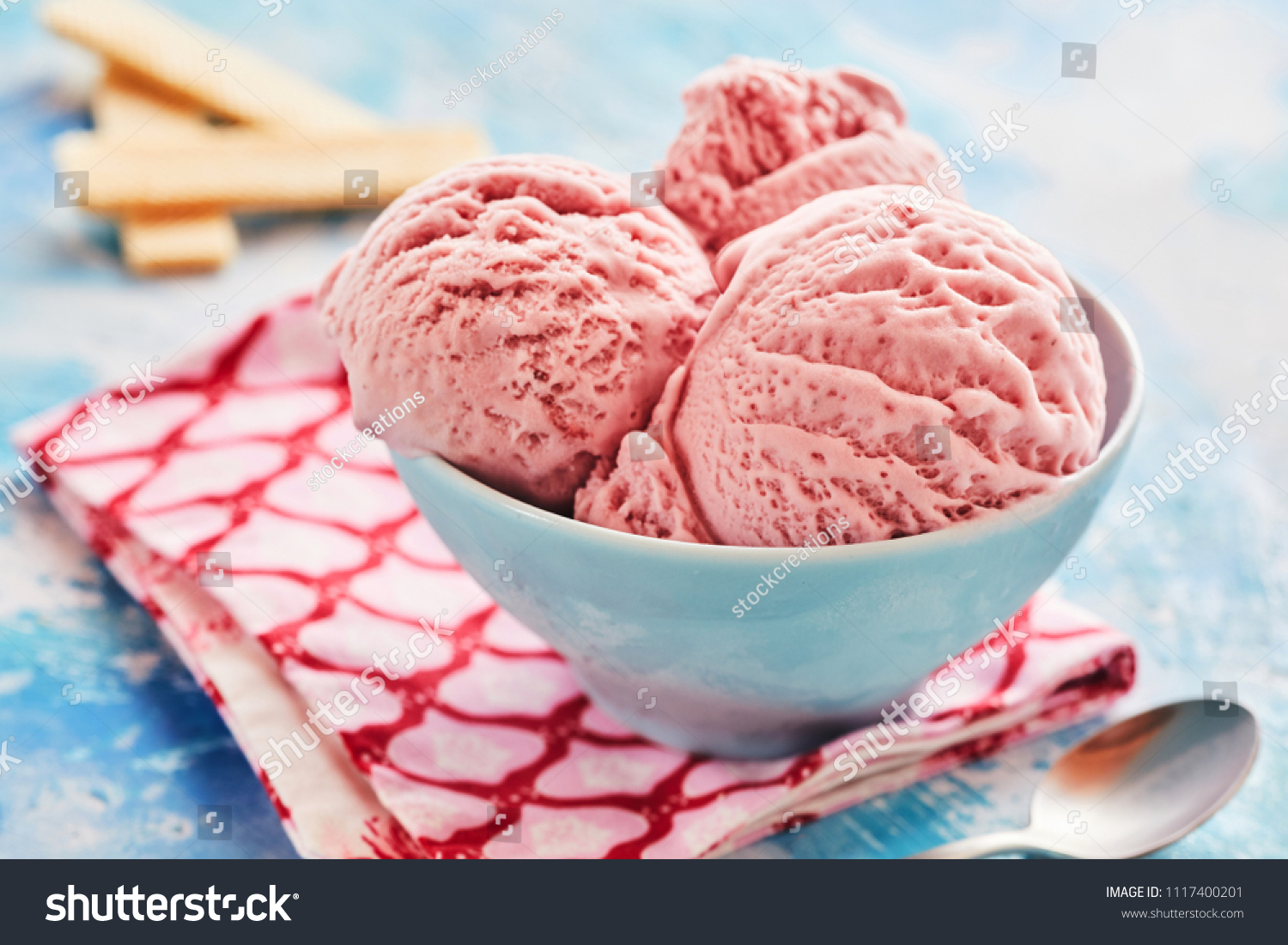Creamy scoops Italian strawberry gelato or ice cream served in a blue bowl for a delicious refreshing summer dessert in a close up view #1117400201