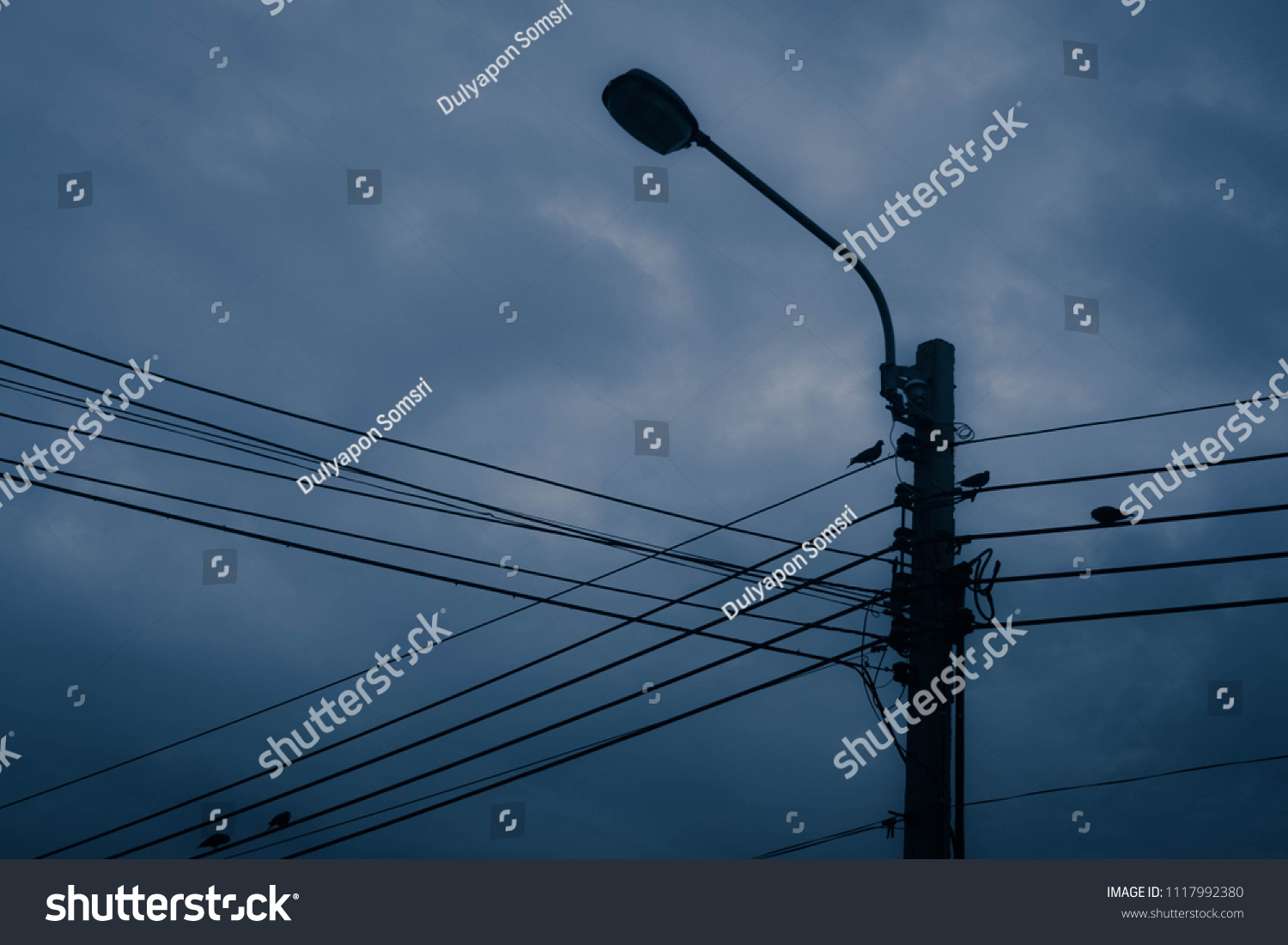 Electricity wire and pole with dark blue clouds and sky background #1117992380