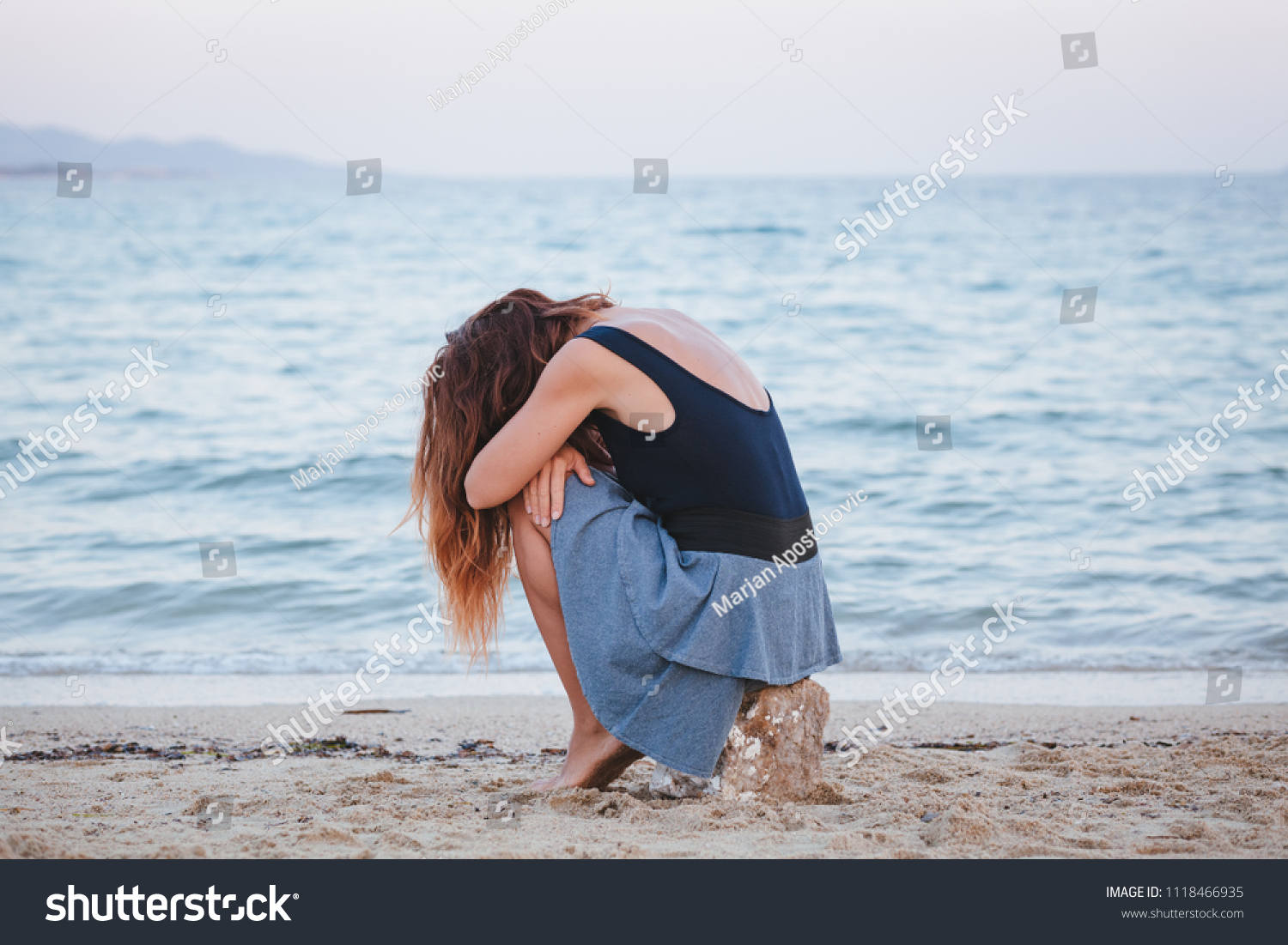Woman alone and depressed sitting at the beach #1118466935