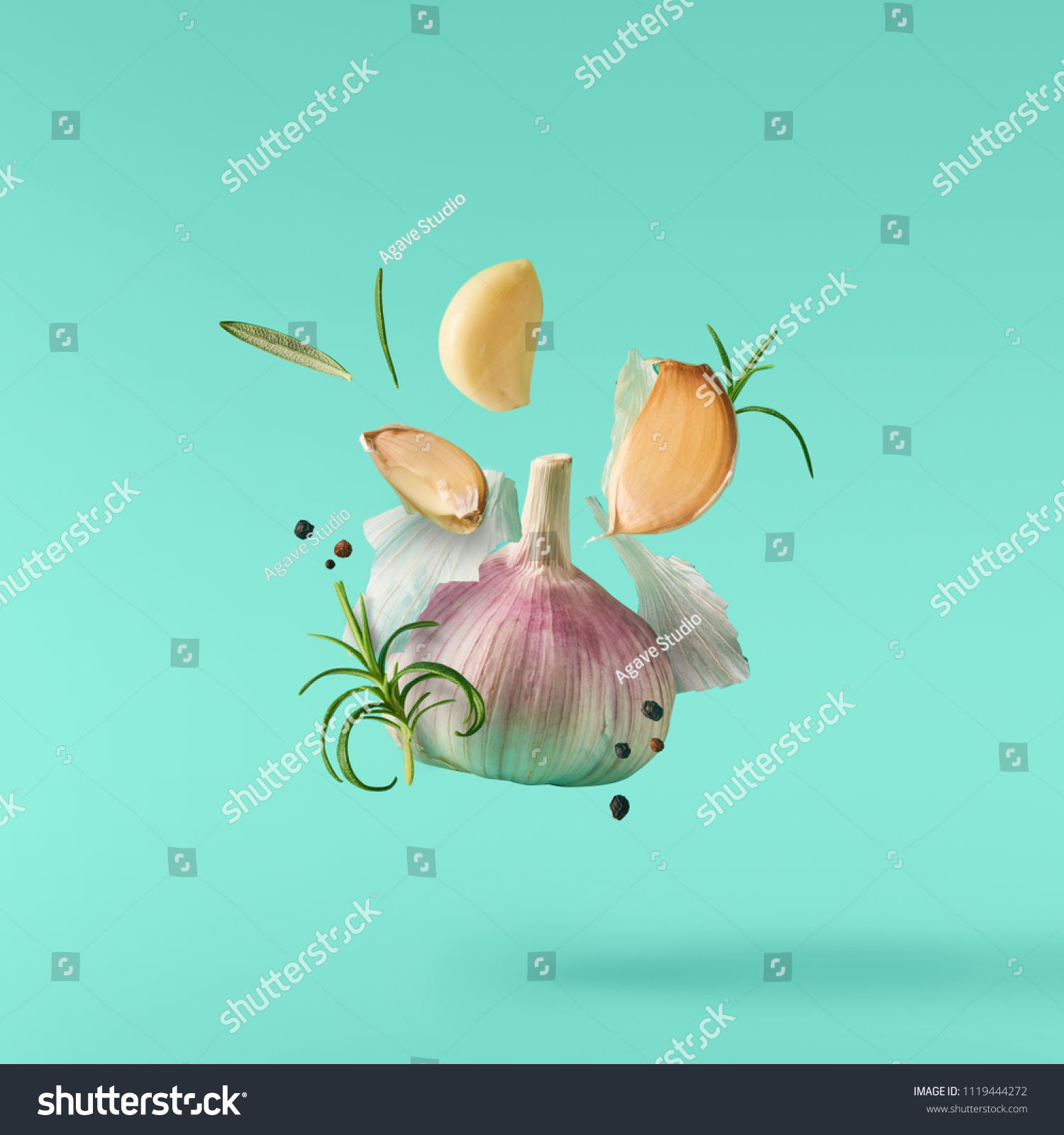 Garlic falling in air with pepper and herbs like rosemary on turquoise background. Spicy food concept #1119444272