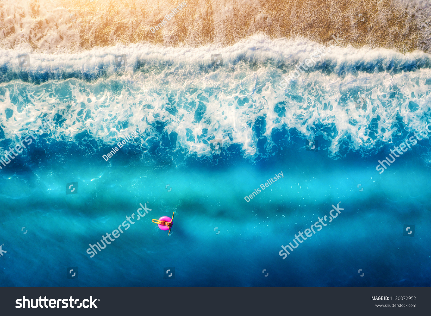 Aerial view of woman swimming on the pink swim ring in the transparent sea and beautiful waves in Europe. Summer landscape with girl, beach, blue water at sunset. Top view. Travel and holiday. Resort #1120072952