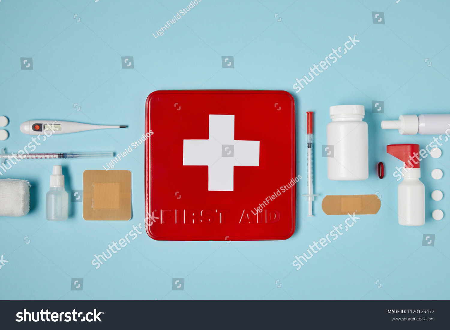 top view of red first aid kit box on blue surface with medical supplies #1120129472