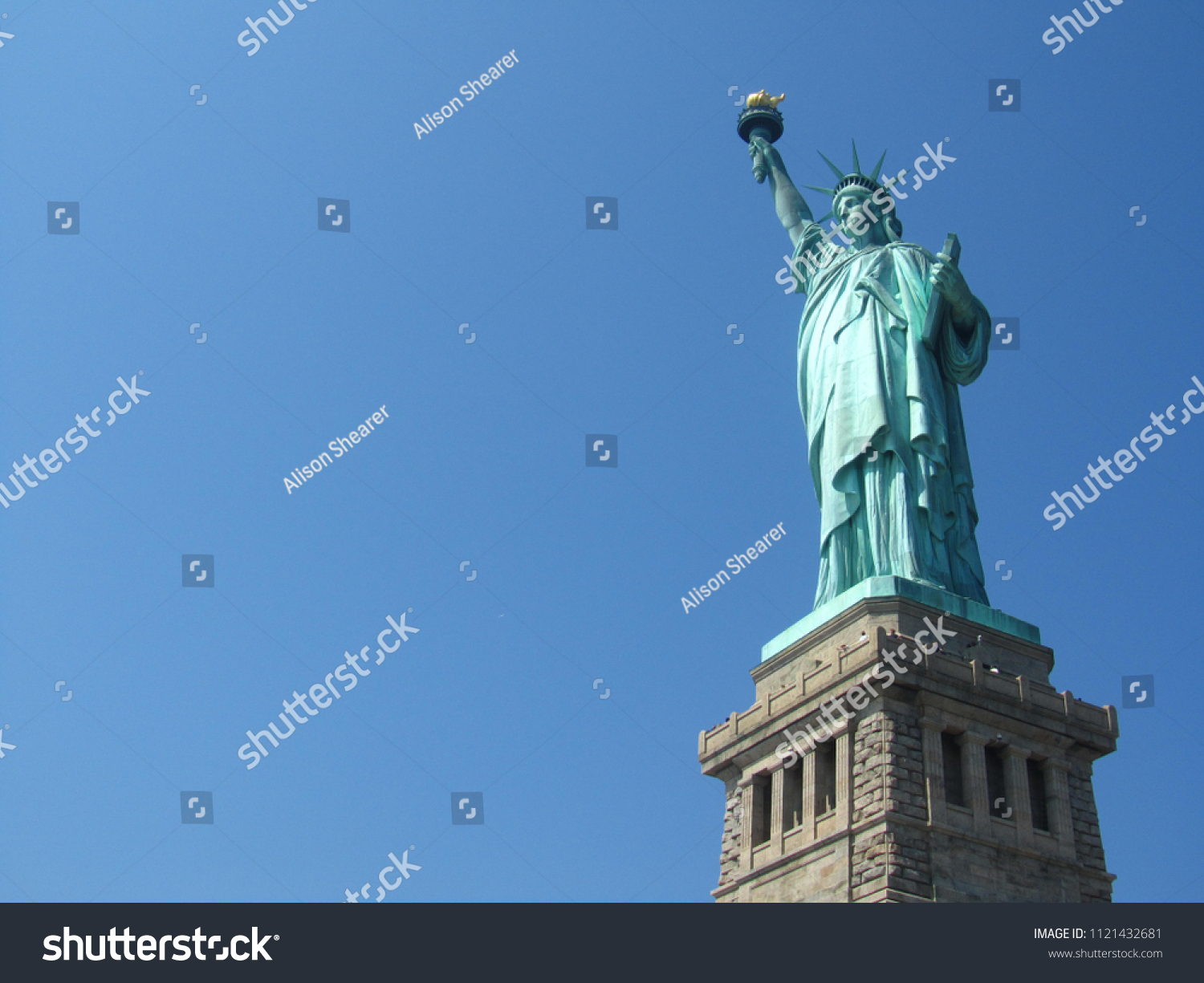 Blue sky with the stature of Liberty in New York.  Includes a part of the base the stature is on. #1121432681