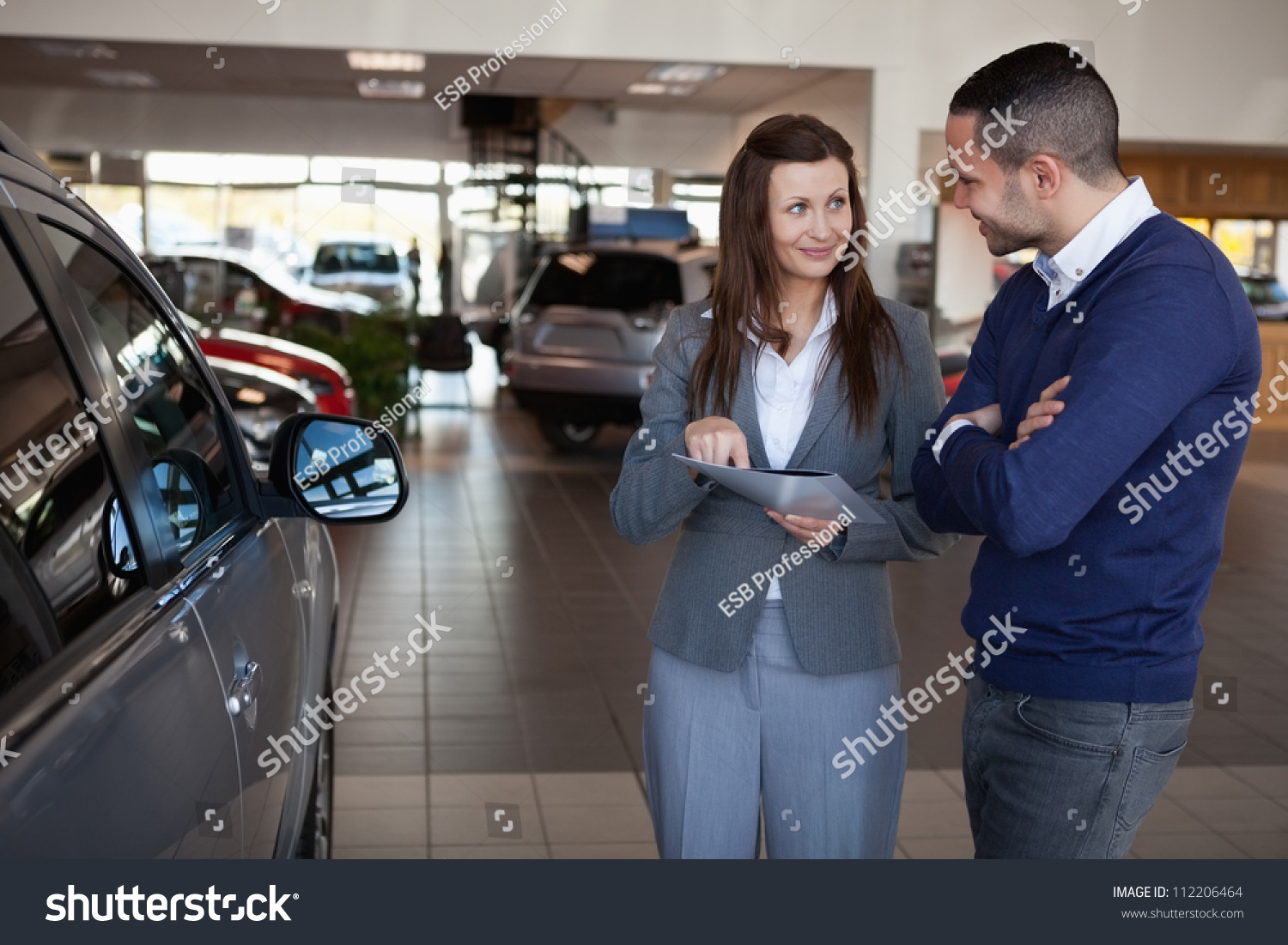 Woman explaining something to a man in a dealership #112206464