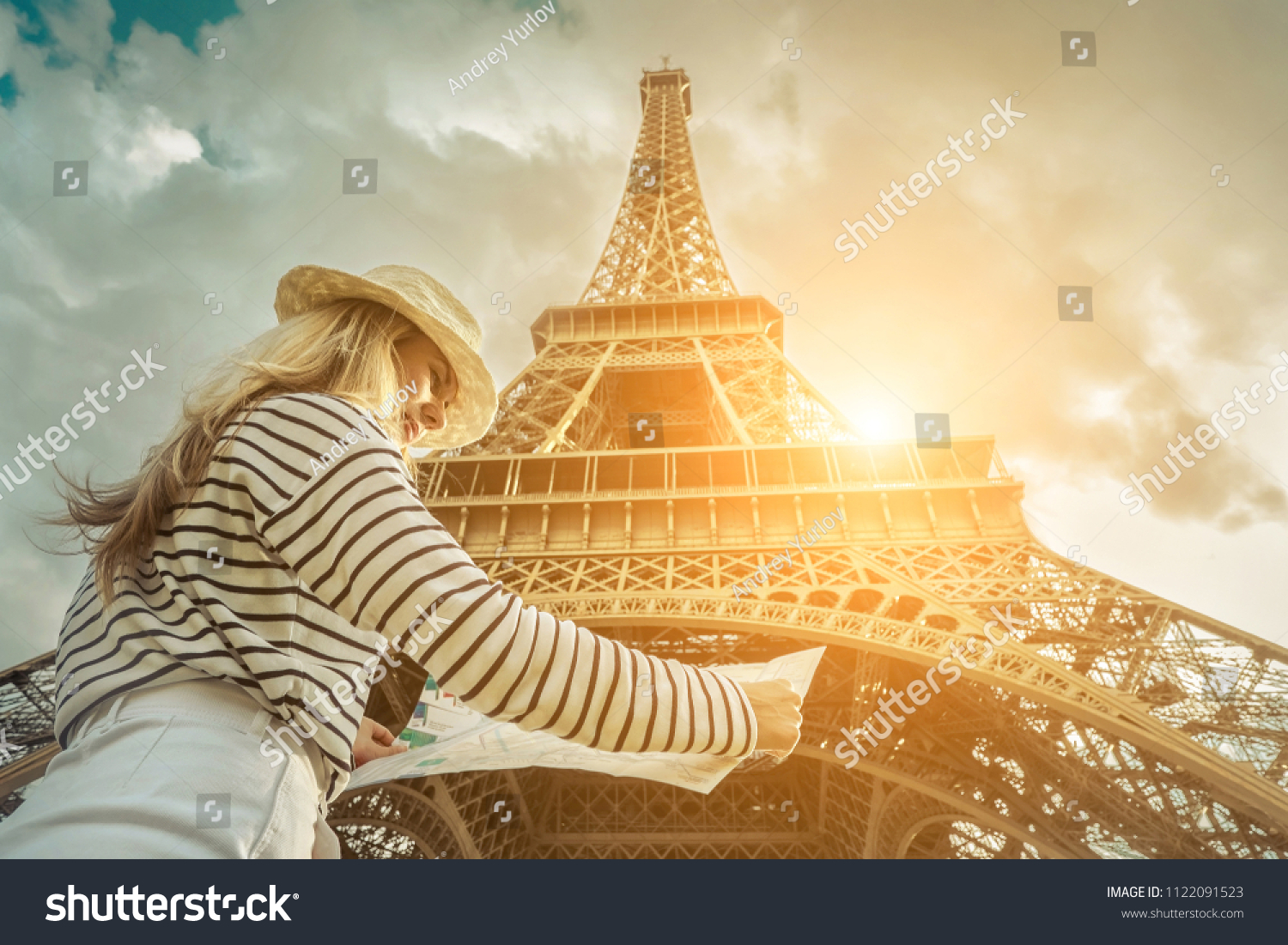 Woman tourist selfie near the Eiffel Tower in Paris under sunlight and blue sky. Famous popular touristic place in the world. #1122091523