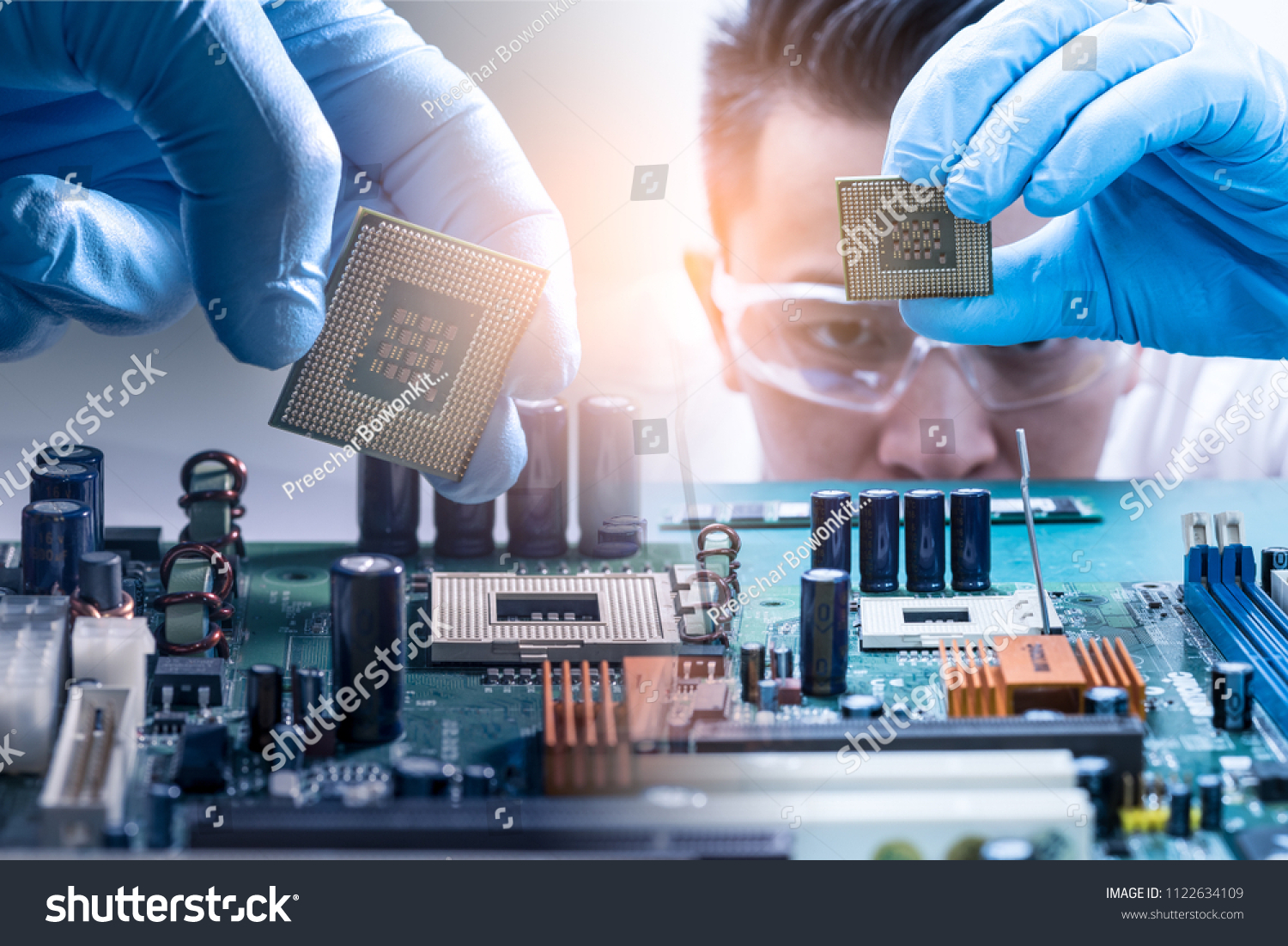The asian technician is putting the CPU on the socket of the computer motherboard. the concept of computer hardware, repairing, upgrade and technology. #1122634109