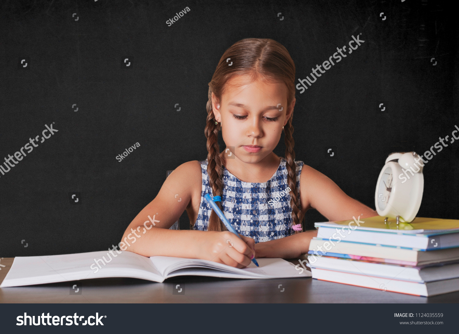 Cute little girl doing homework, reading a book, coloring pages, writing and painting. Children paint. Kids draw. Preschoolers learn to write and read. Creative toddler . #1124035559