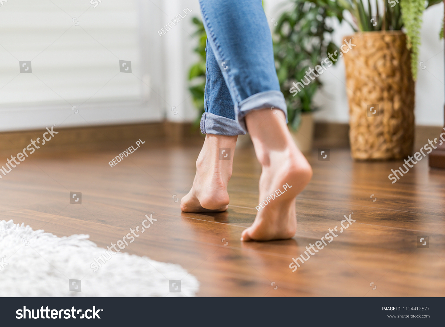 Floor heating. Young woman walking in the house on the warm floor. Gently walked the wooden panels. #1124412527