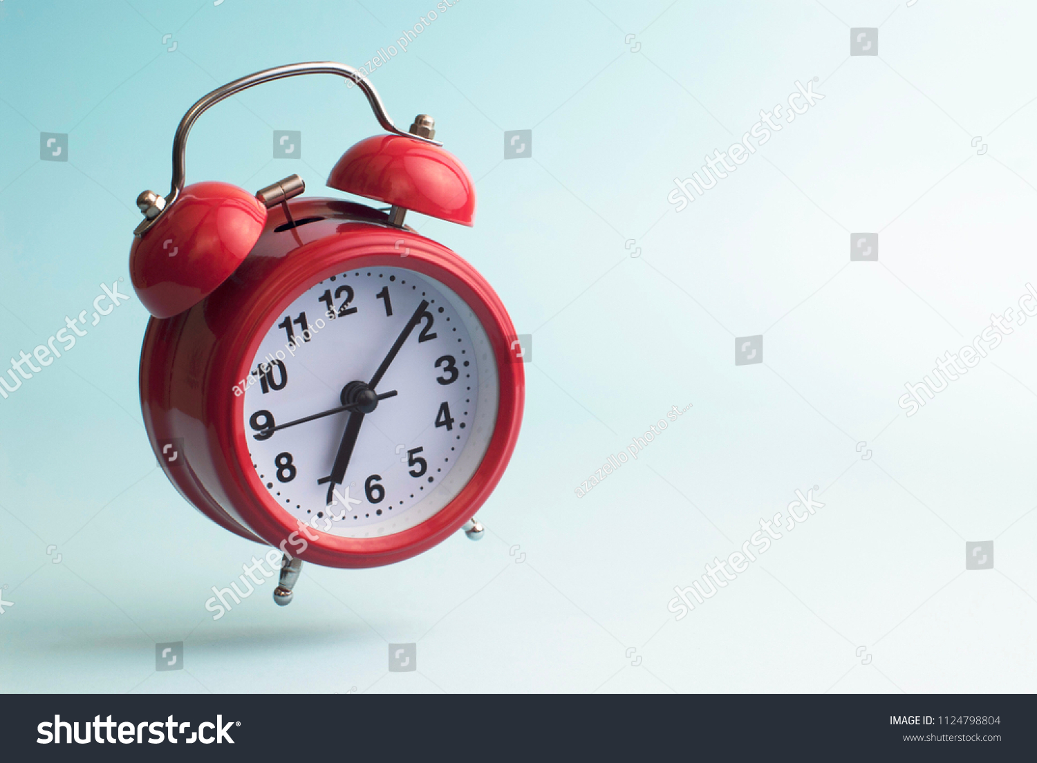 Red alarm clock. Flying alarm clock. Red alarm clock on a blue background. #1124798804