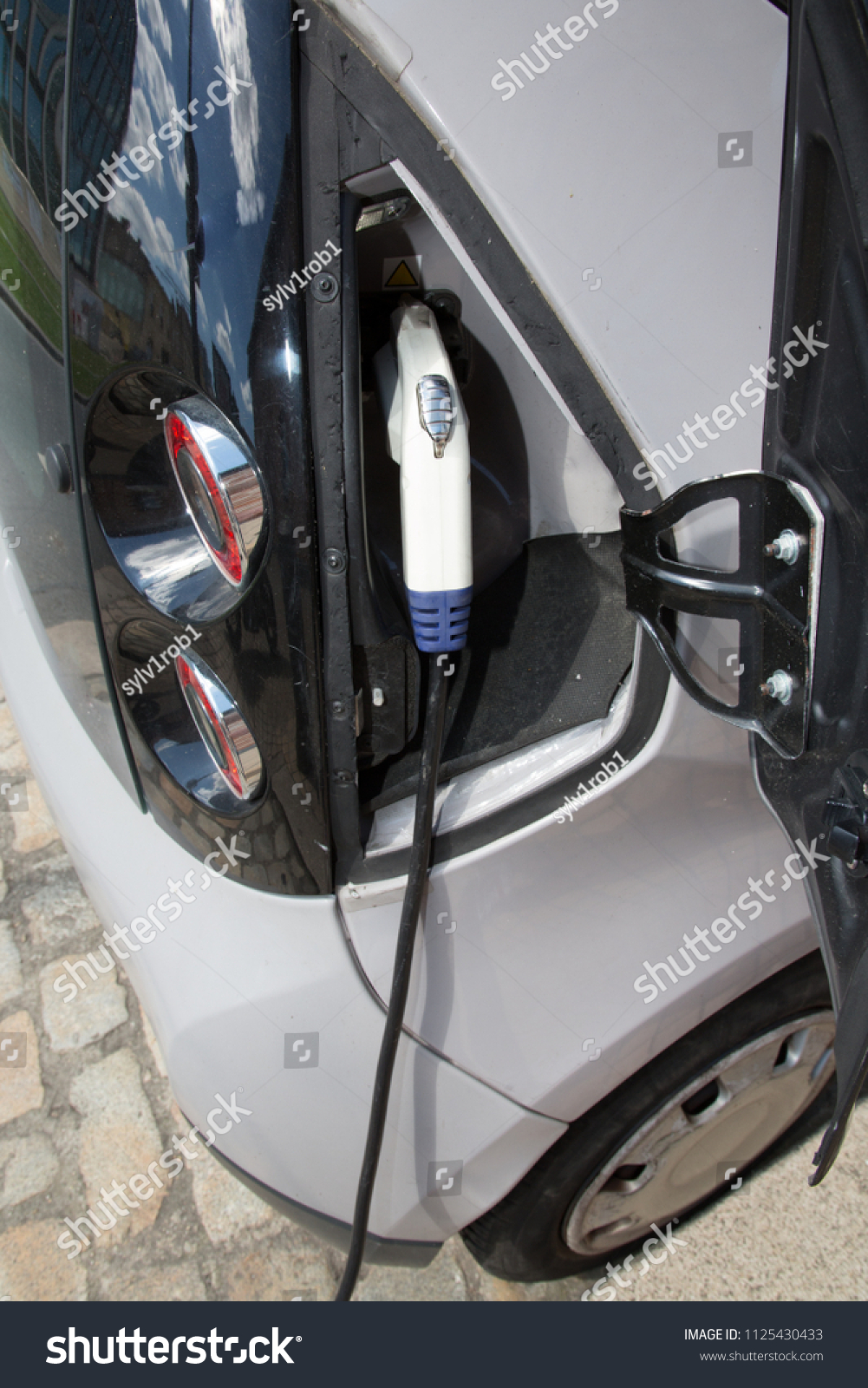 electric car are charged by charging stations in the parking lot #1125430433