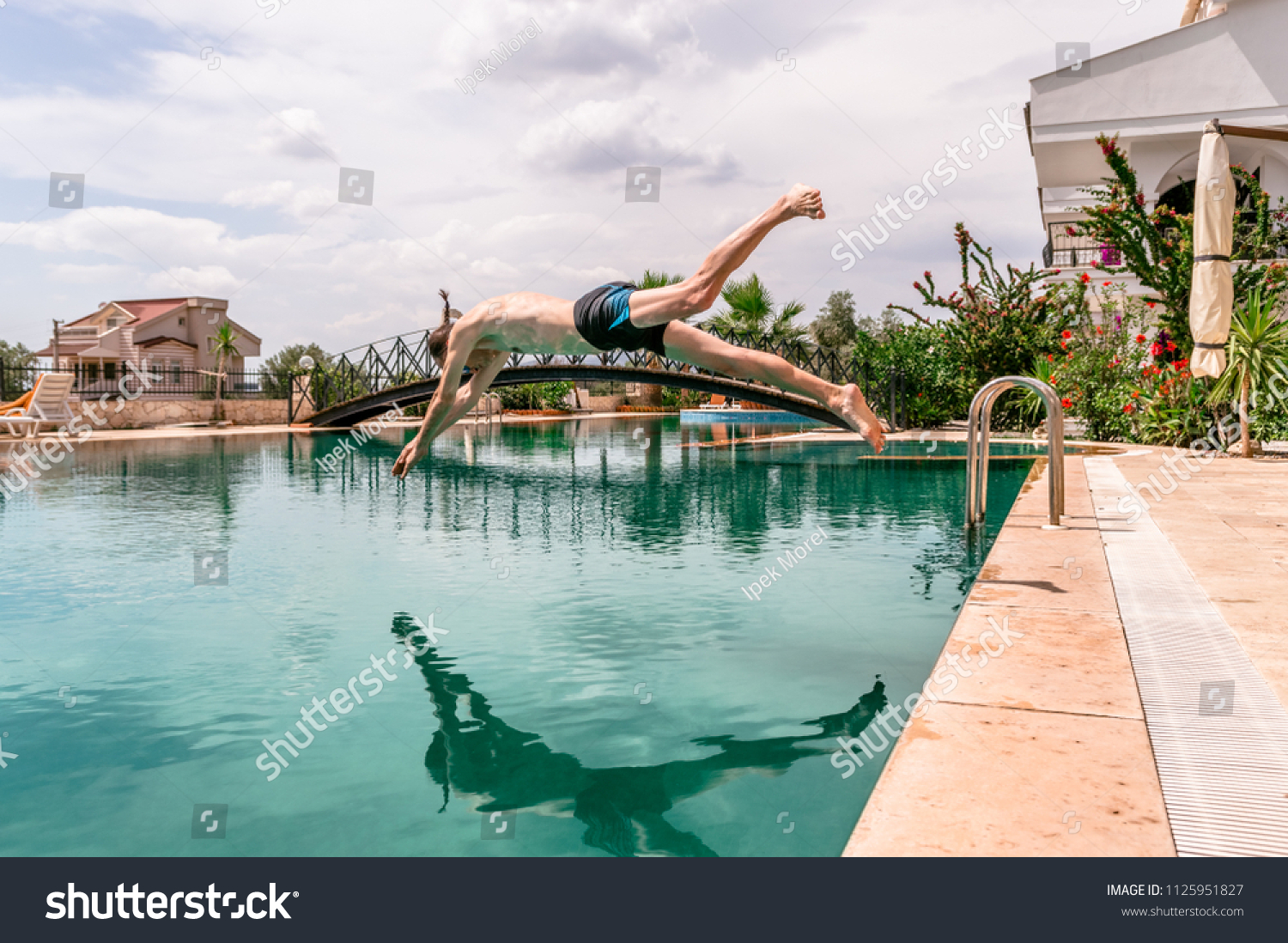 Sexy fit man diving in the swimming pool in a resort #1125951827