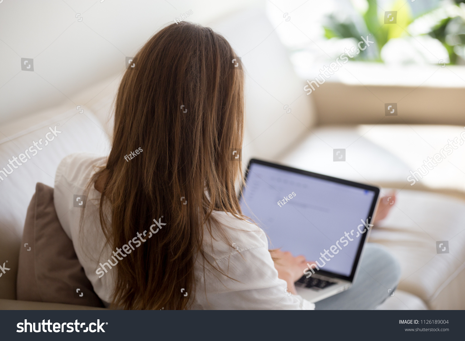 Woman using laptop for typing email at home, female blogger writer writing text for blog post, unemployed lady searching for work opportunities creating cover letter applying for new job, rear view #1126189004