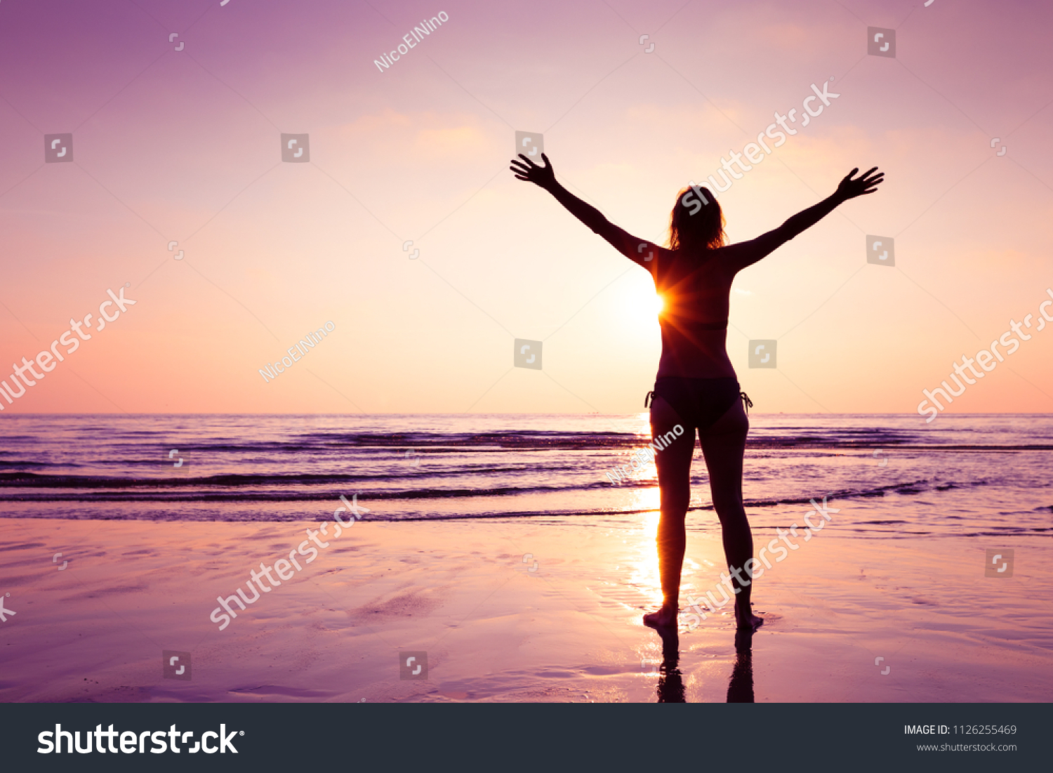 Happy joyful woman spreading hands on the beach at sunset, cheerful emotion and mindfulness, balance, mindful thinking #1126255469