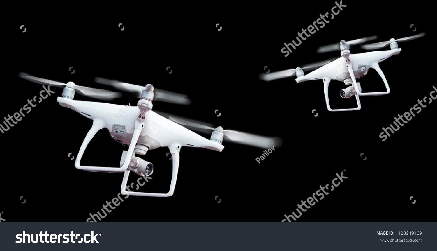 Isolated white drone with twirled propellers on black background #1128949169