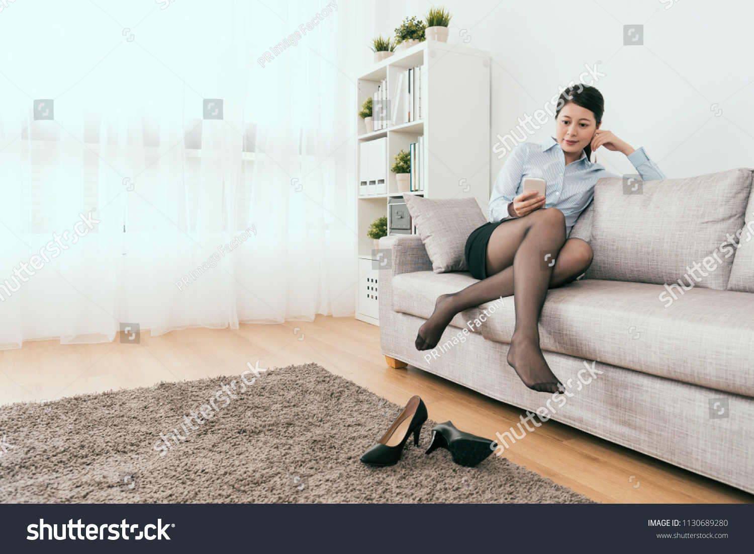 beautiful business lady sitting on the sofa using smartphone take rest in the living room at home #1130689280