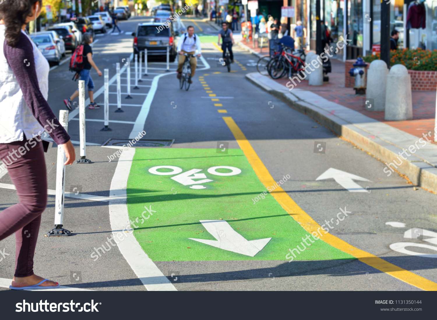 Two-way protected bike lanes with pavement markers, striped median, buffer zone and flexible delineators in city street #1131350144