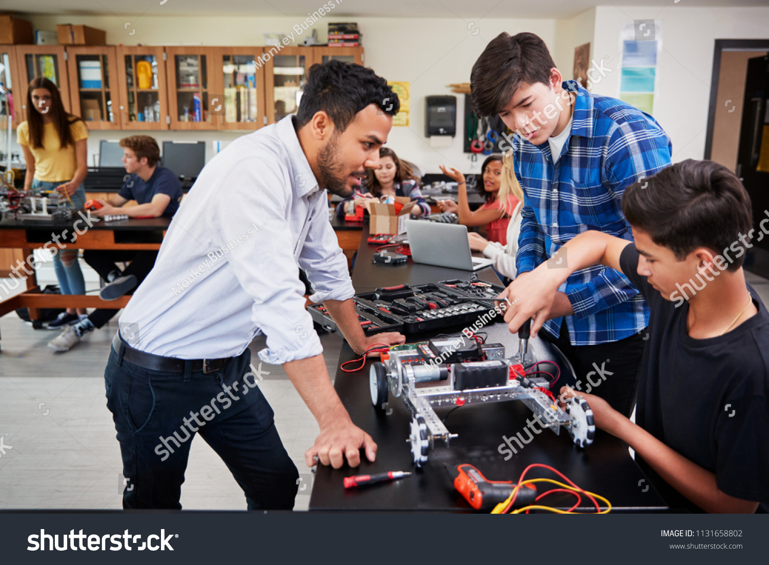 Teacher With Male Pupils Building Robotic Vehicle In Science Lesson #1131658802
