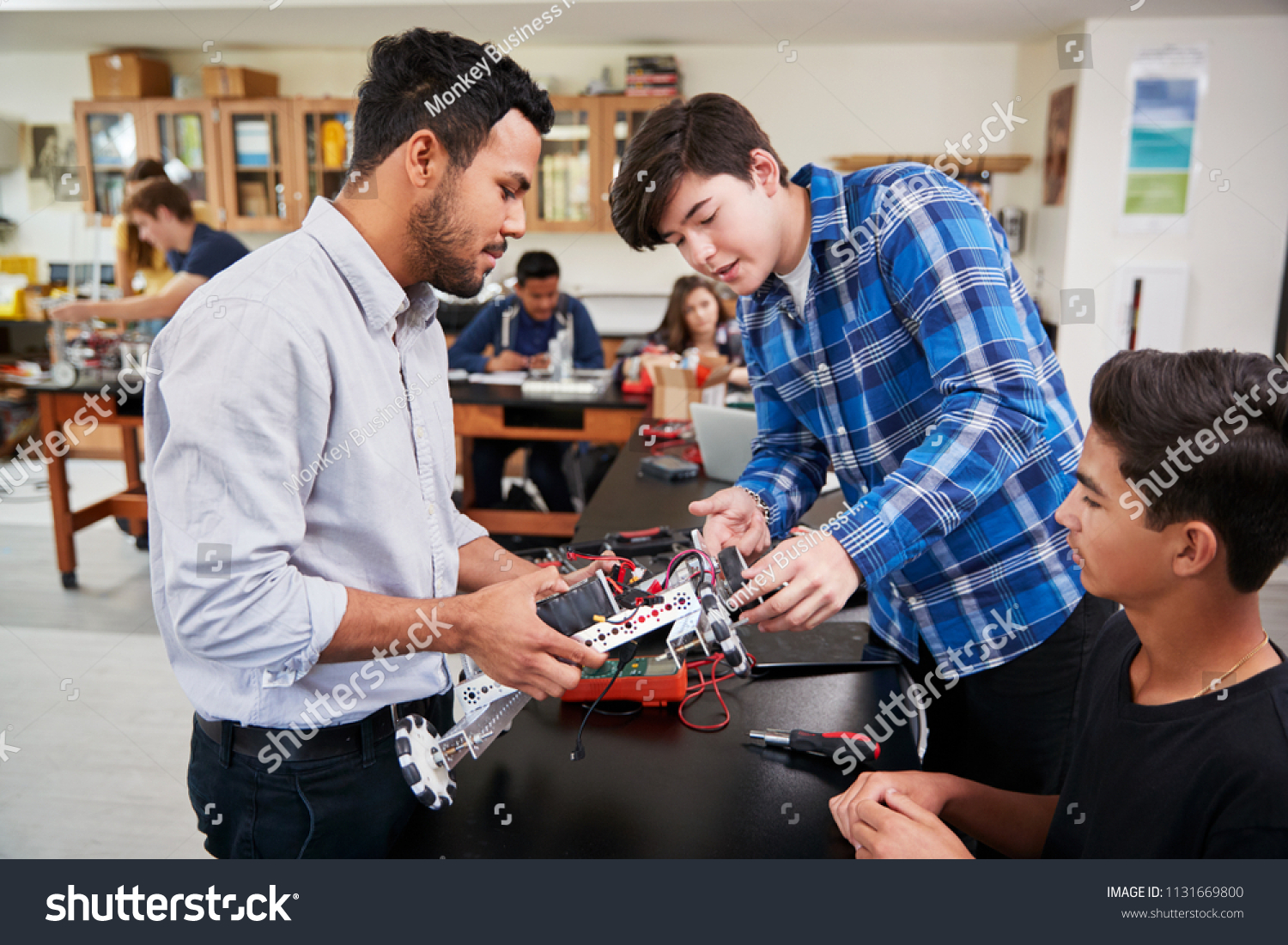 Teacher With Male Pupils Building Robotic Vehicle In Science Lesson #1131669800