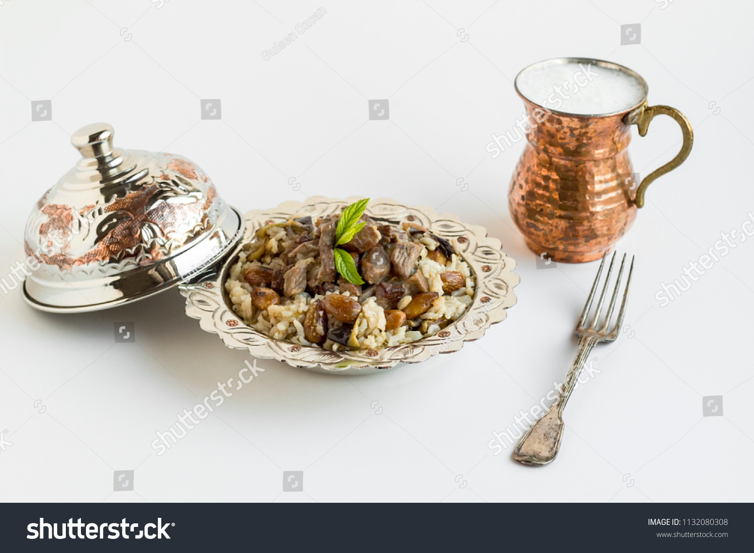 Traditional Turkish Islamic Festival,Food with braised meat,Kavurma and pilaff in vintage copper bowl on white with drink and fork #1132080308