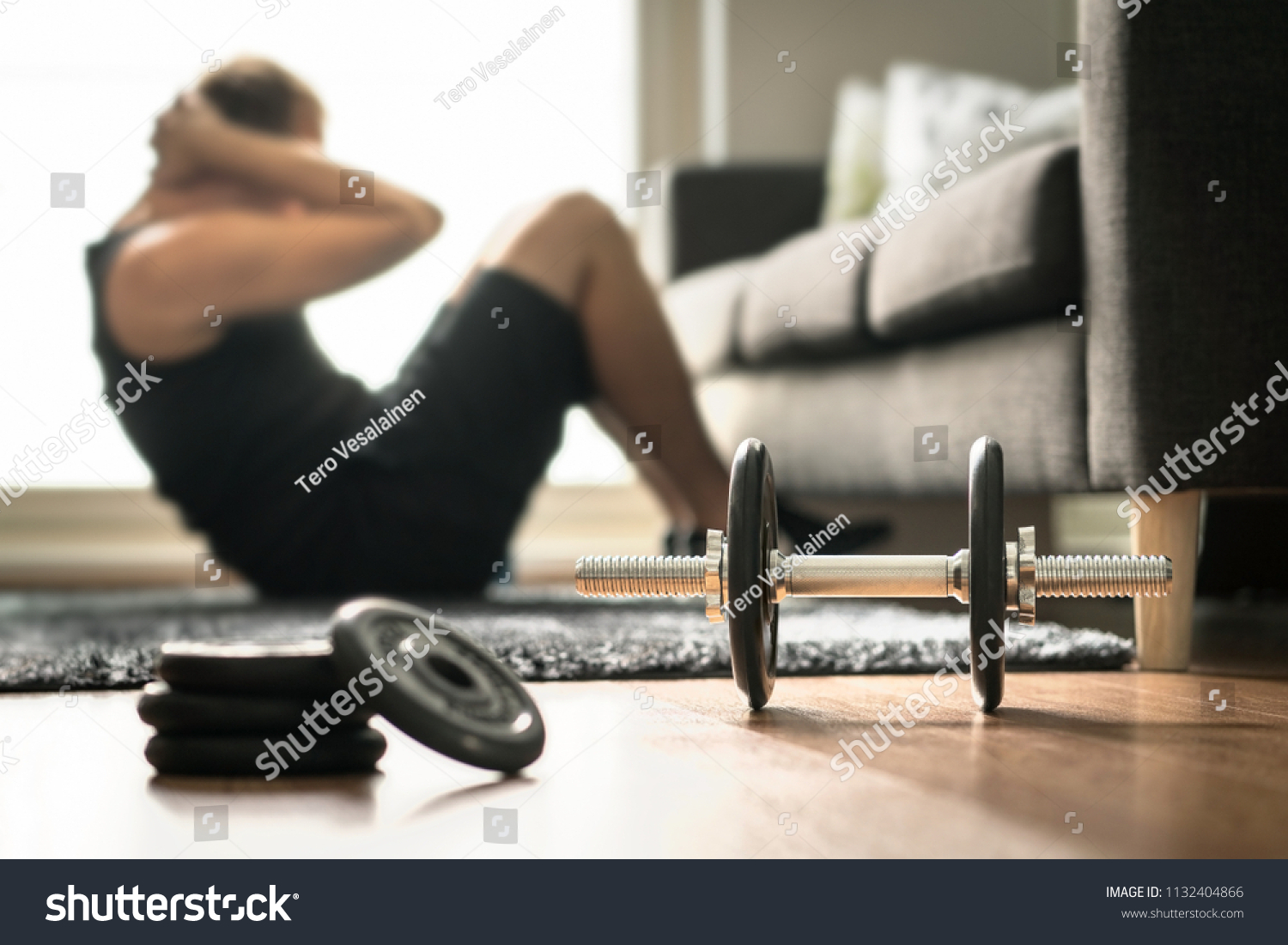 Home workout. Man doing ab training and crunches in living room gym. Guy doing sit ups. Warm up before weight exercise. Fitness concept with dumbbell and athlete. #1132404866