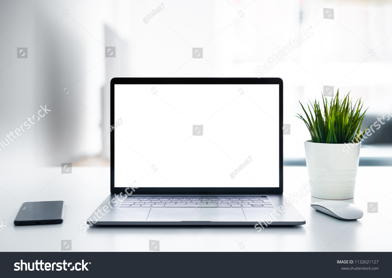 Laptop with blank screen on white table with mouse and smartphone. Home interior or office background #1132621127