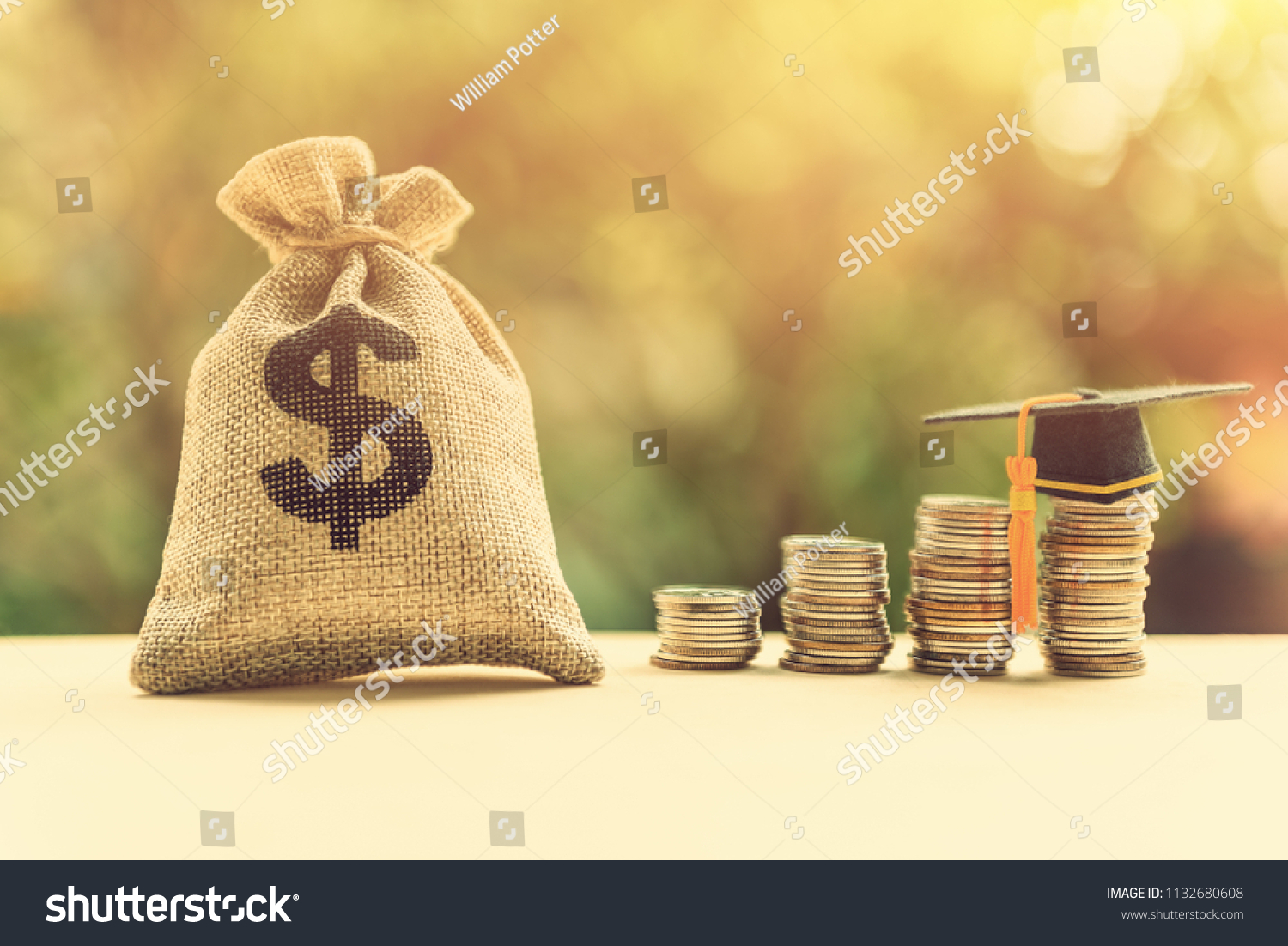 Money cost saving for goal and success in school, education concept : US dollar / cash in hemp bags or burlap sacks, a graduation cap or hat on highest row of coins, depicts final study or achievement #1132680608