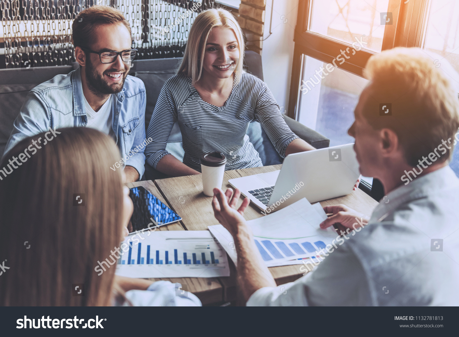 Business People in Casual Wear Discussing Affairs. Four Smart Colleagues Using Laptop and Drinking Coffee. They Have Discuss Hard Project. Professional relationships Concept. Modern Free Workplace. #1132781813