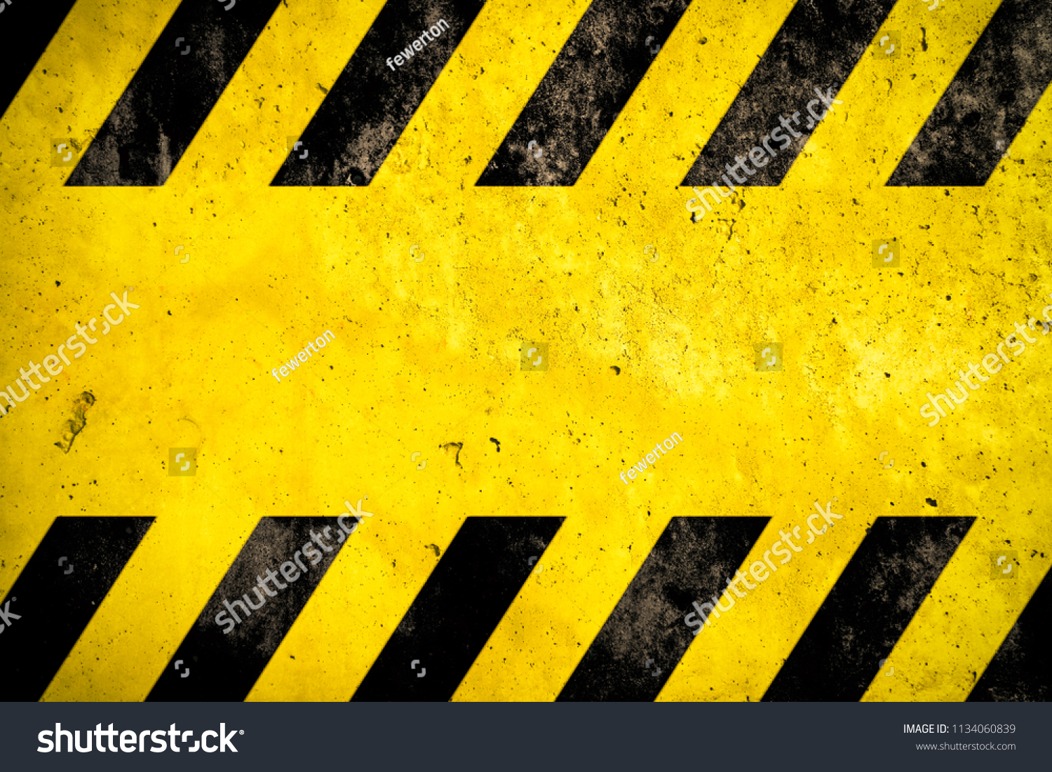 Warning danger background with yellow and black stripes painted over yellow concrete wall facade texture and empty space for text message in the middle. Concept image for caution, danger and hazard. #1134060839