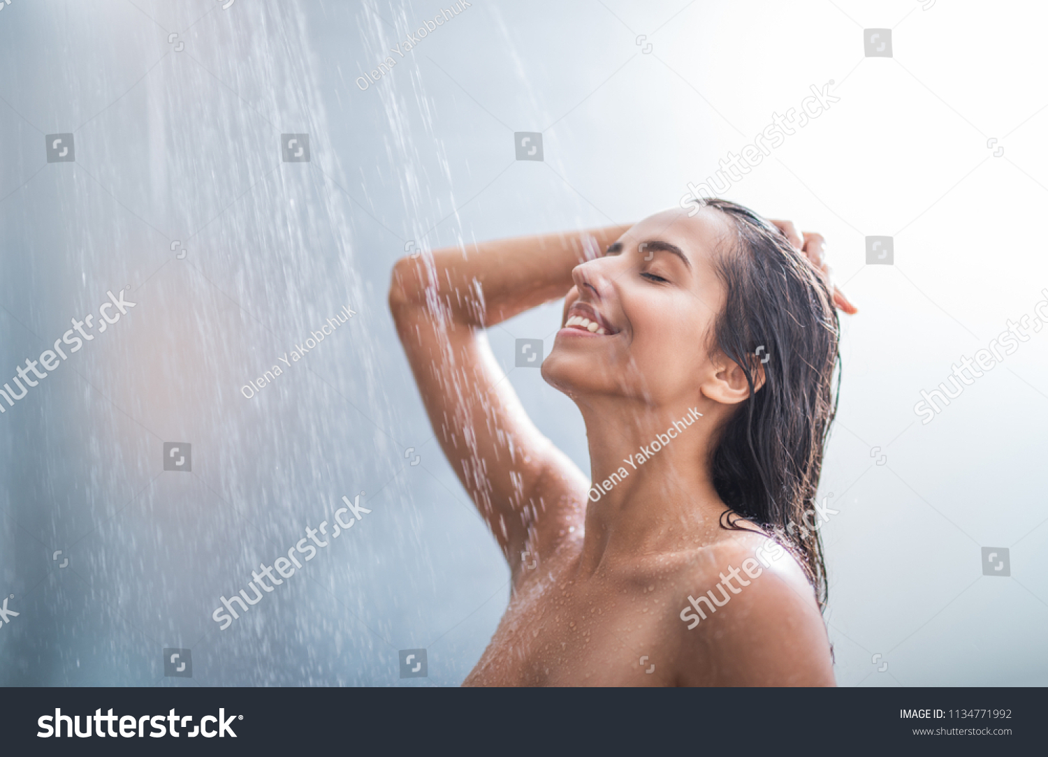 Side view happy woman washes body and hair under stream of hot water #1134771992