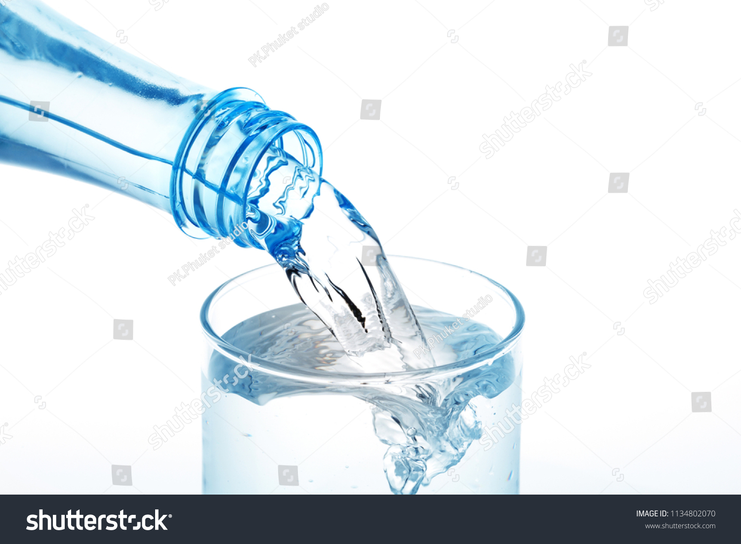 Pouring water from bottle into glass on white background #1134802070