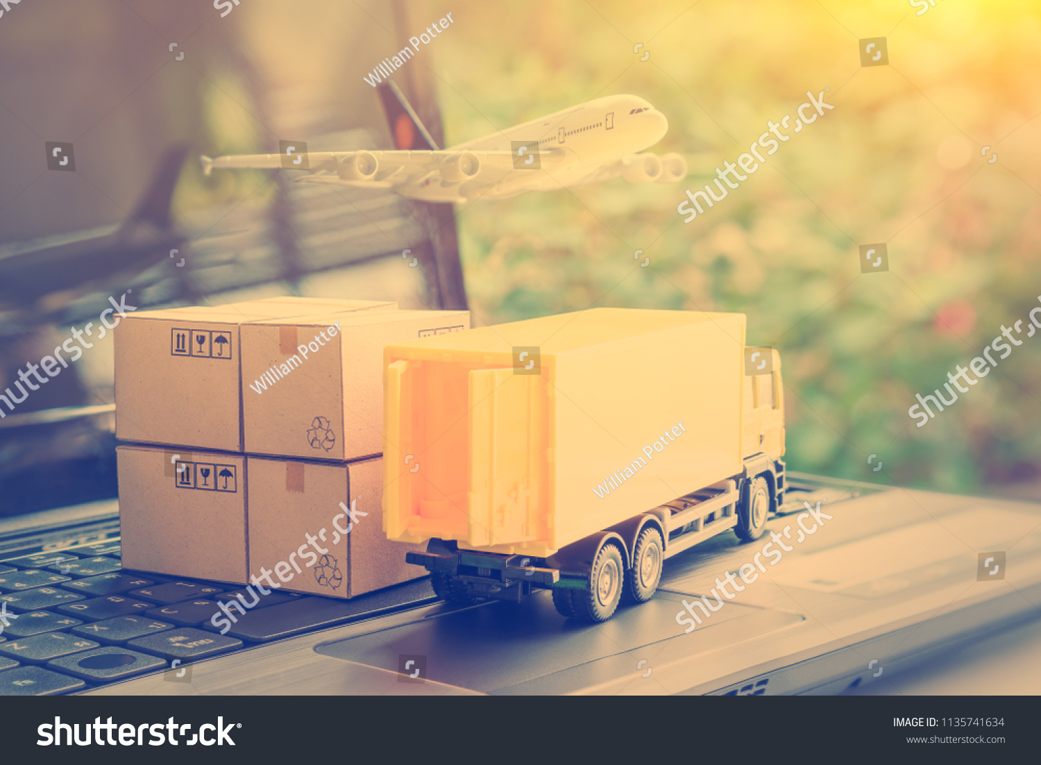 Air courier / freight forwarder or shipping service concept :  Boxes, a truck, white plane flies over a laptop, depicts customers order things from retailer sites via the internet and ship worldwide. #1135741634