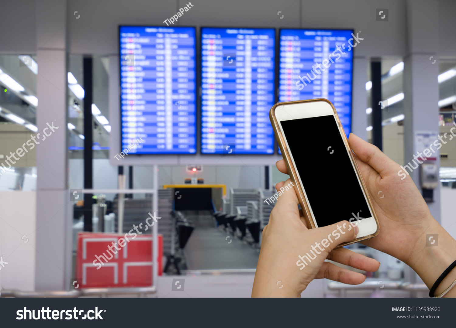 Mock up image. Woman, traveler using smart mobile phone making online check-in with abstract blurred flight schedule board at the international airport to travel on weekends. #1135938920