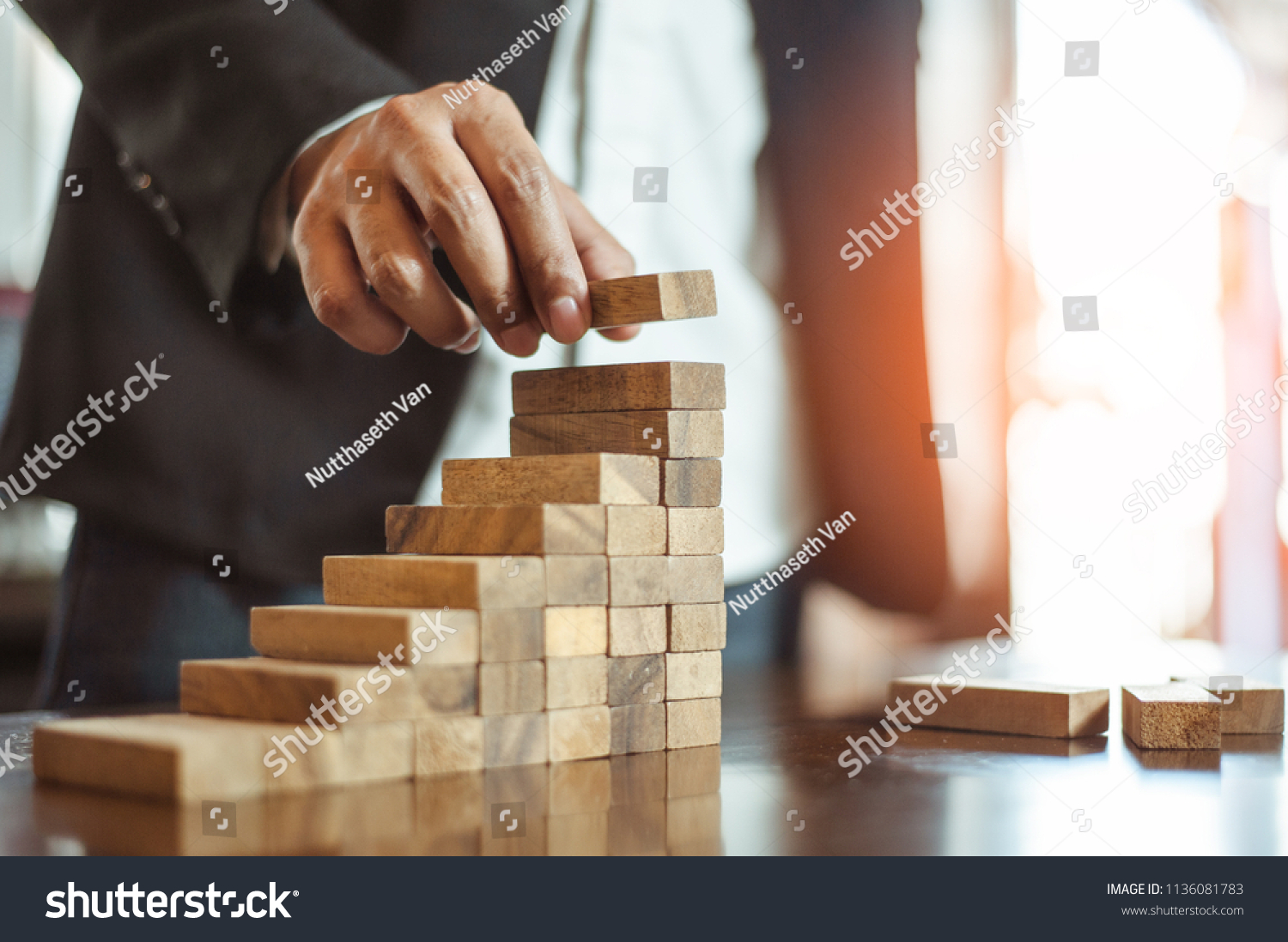 plan and strategy in business.risk concept.hand of man has piling up and stacking a wooden block.Businessman Building The Success. #1136081783