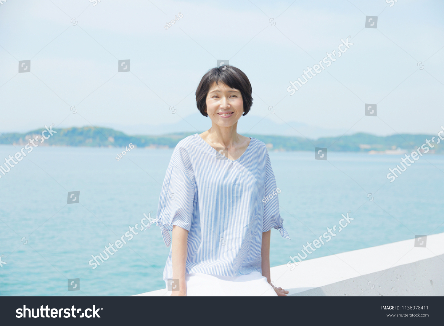 Asian woman sitting down on the breakwater #1136978411