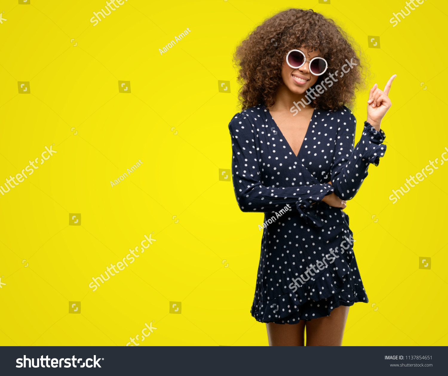 African american woman with sunglasses and summer dress very happy pointing with hand and finger to the side #1137854651