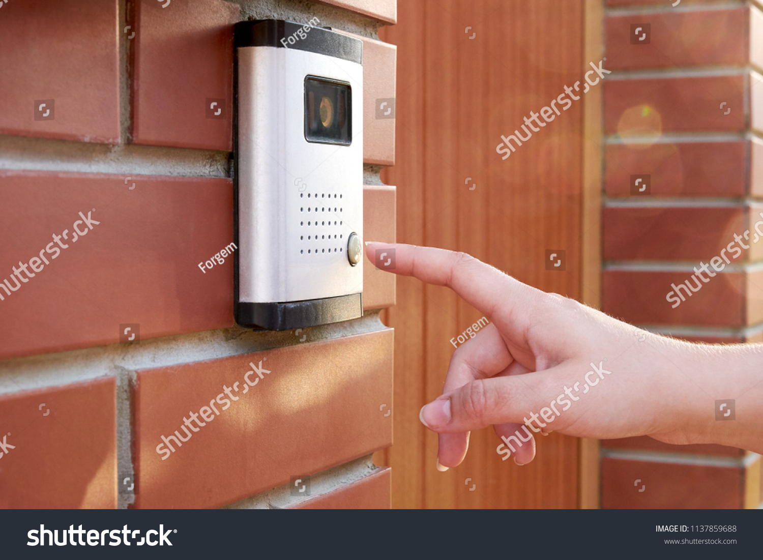 The female hand presses a button doorbell with camera and intercom #1137859688