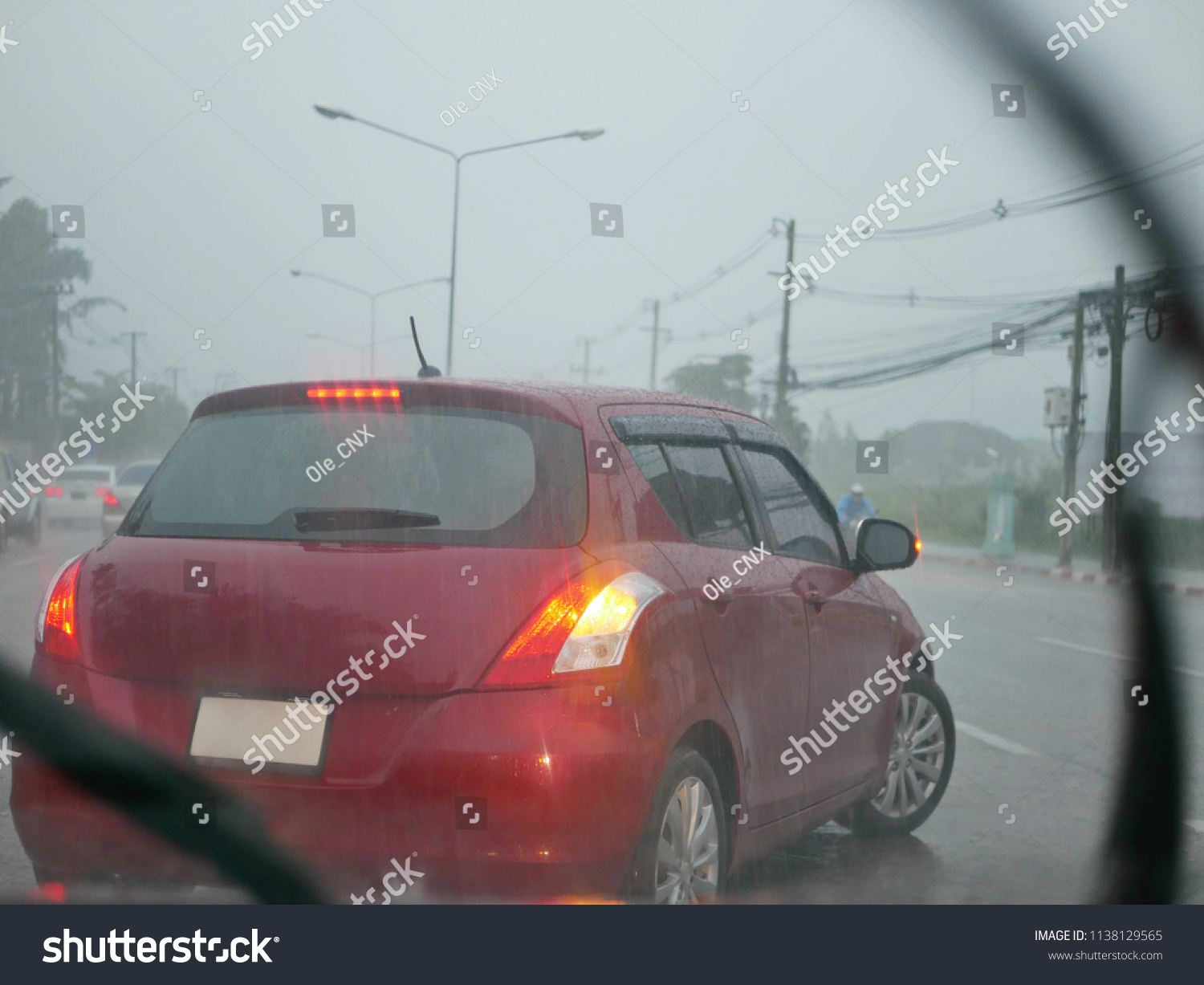 A car with its signal light on carefully making a U-turn in a heavy rain on a rainy day - driver's perspective from another car behind  #1138129565