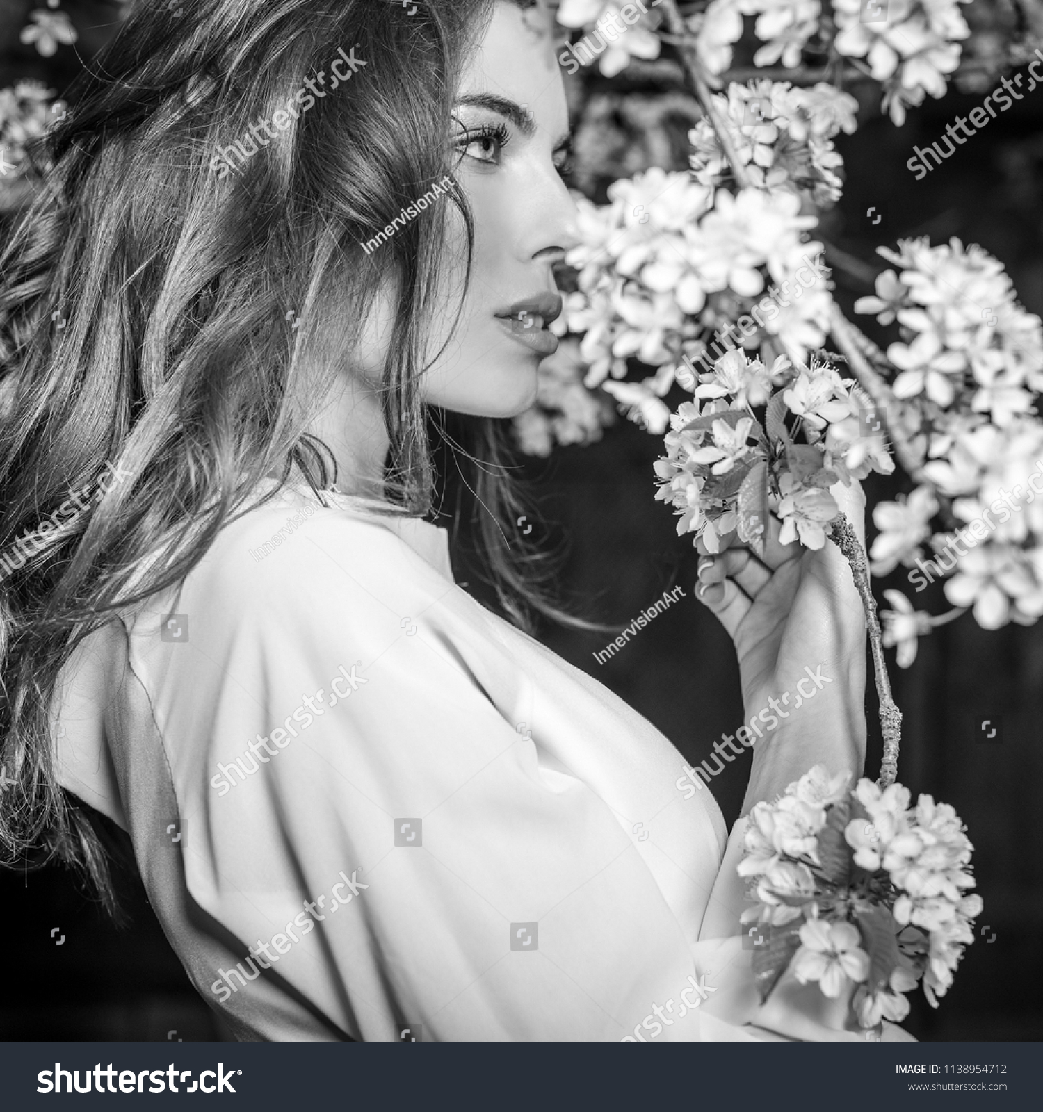 Portrait of beautiful young woman in autumn garden against blooming cherry. Black-white photo. #1138954712