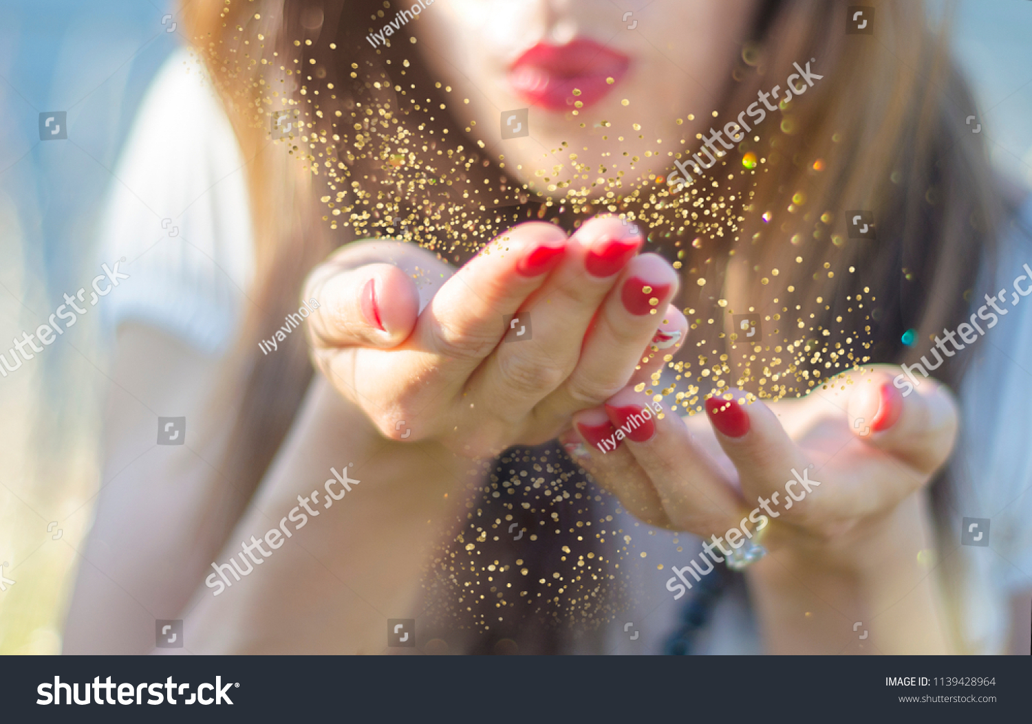 Beauty young woman blowing magic gold glitter dust from her hand. #1139428964