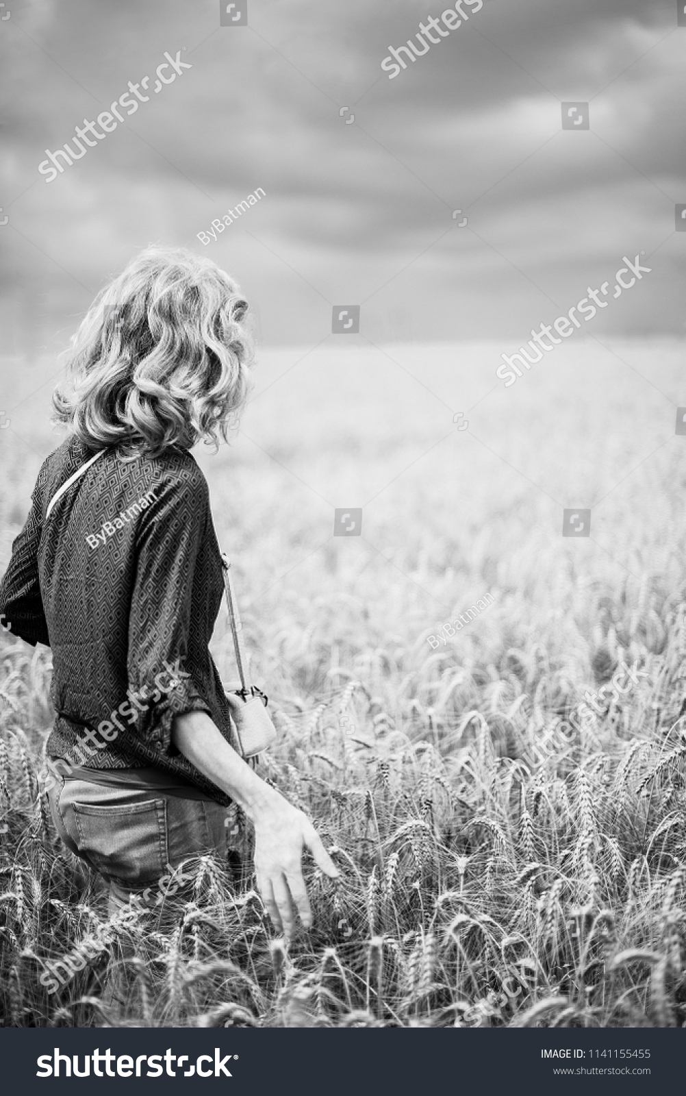 woman in a wheat field. year-old black and white landscape. the figure of the girl in the ears of wheat. #1141155455