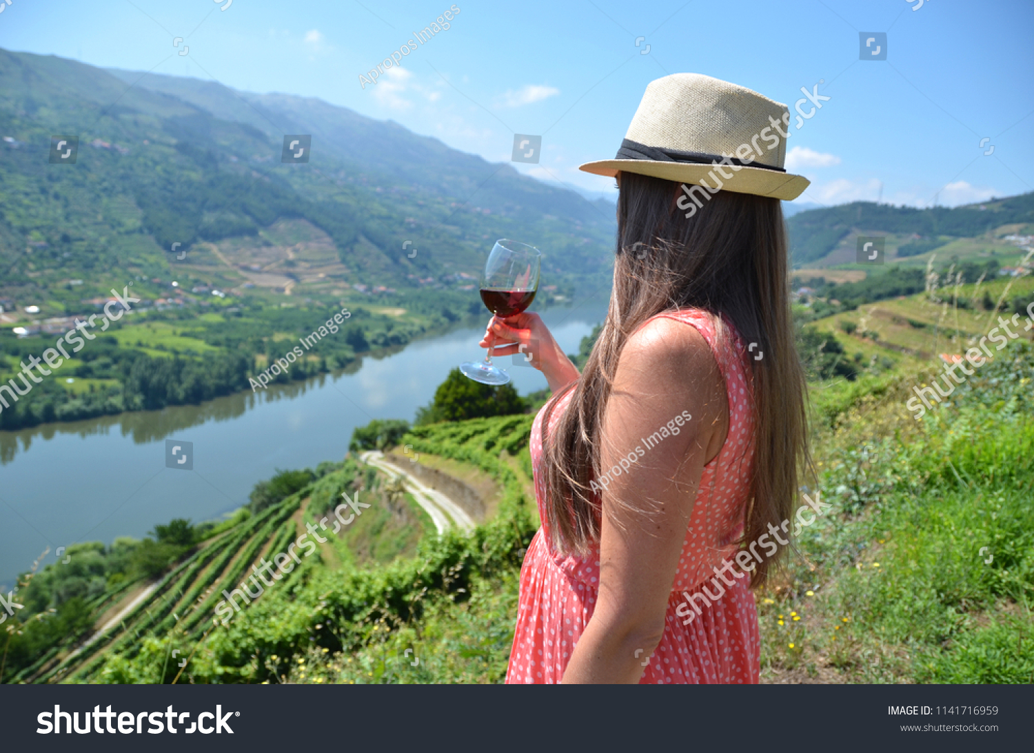 Girl with a glass of wine looking to the vineyards in Douro Valley, Portugal #1141716959