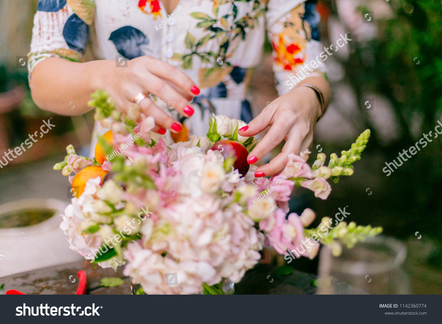 Close ups of woman florist's hands creating floral arrangements in garden #1142360774